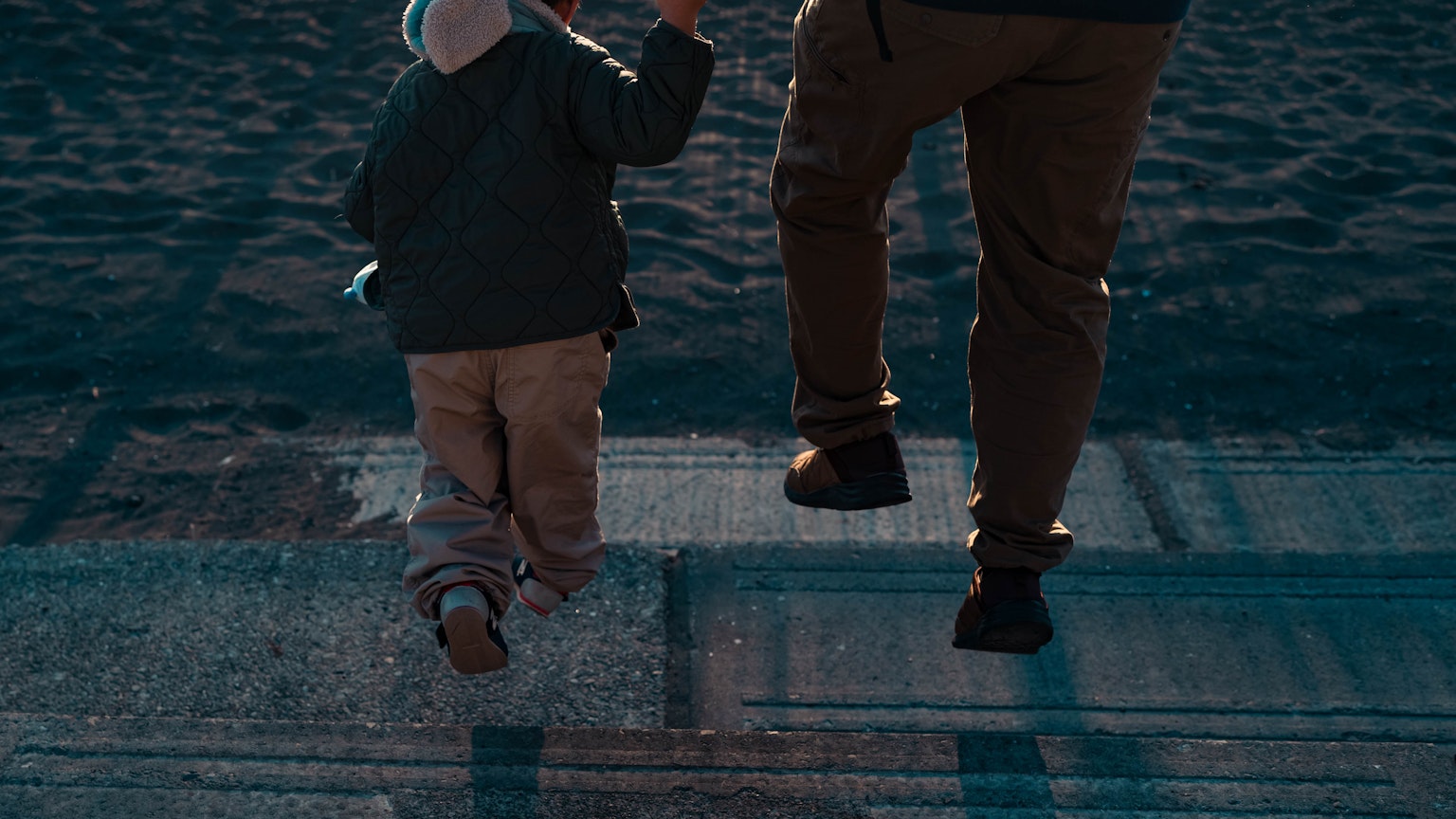 Un genitore e un bambino che camminano mano nella mano visti di spalle