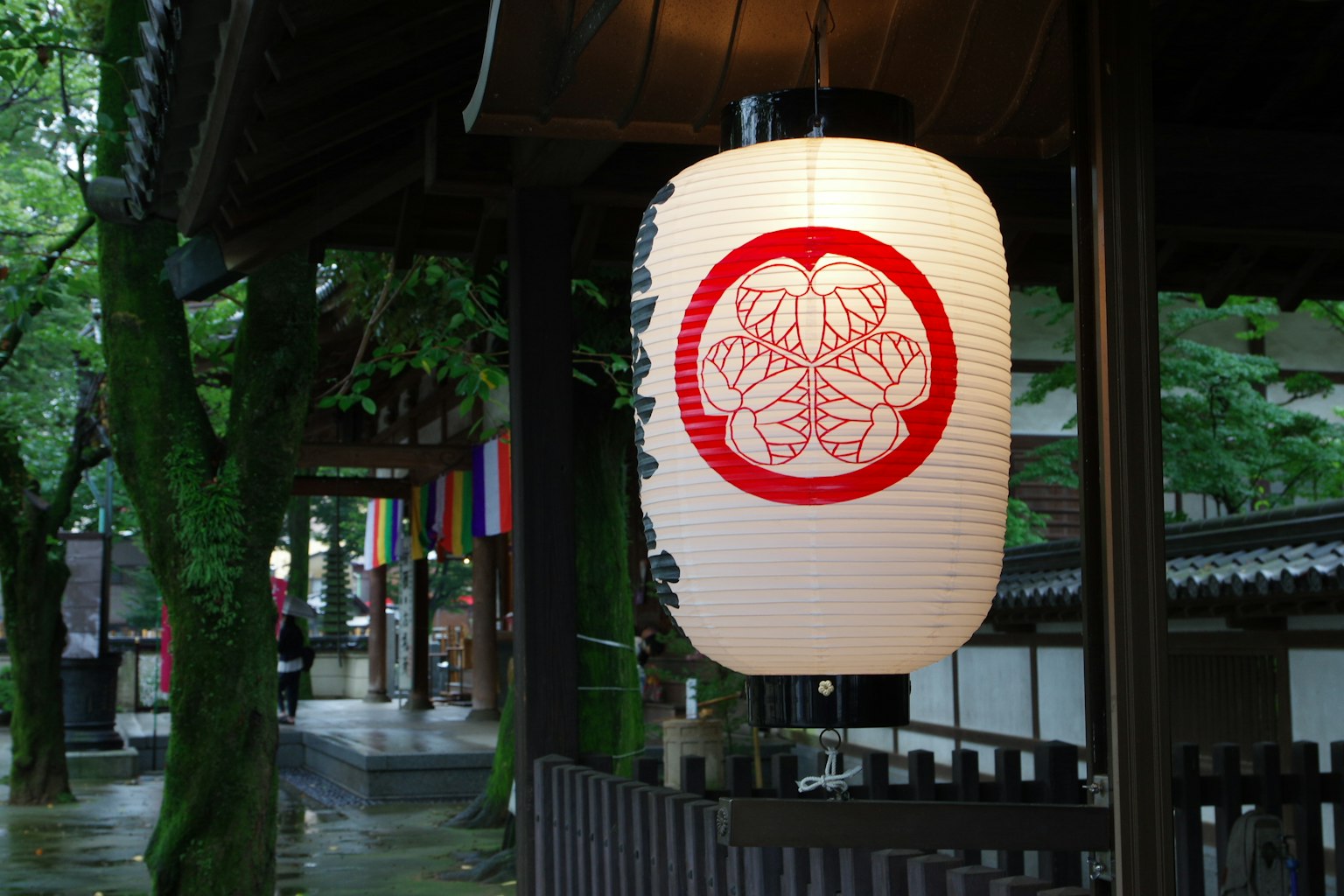 Japanese lantern with red floral design hanging in a serene garden