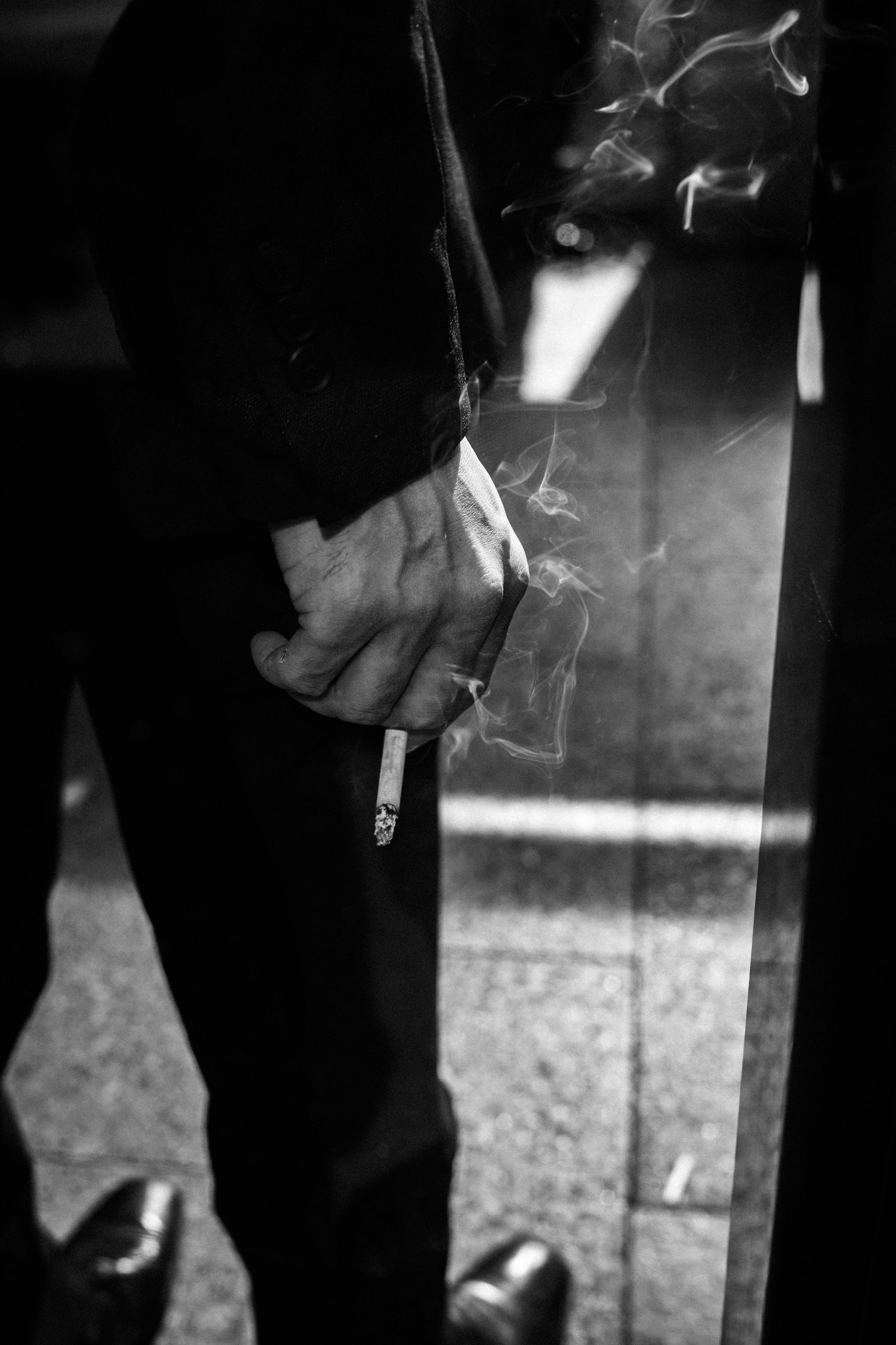 Eine Hand, die eine Zigarette hält, mit Rauch in einem Schwarz-Weiß-Foto
