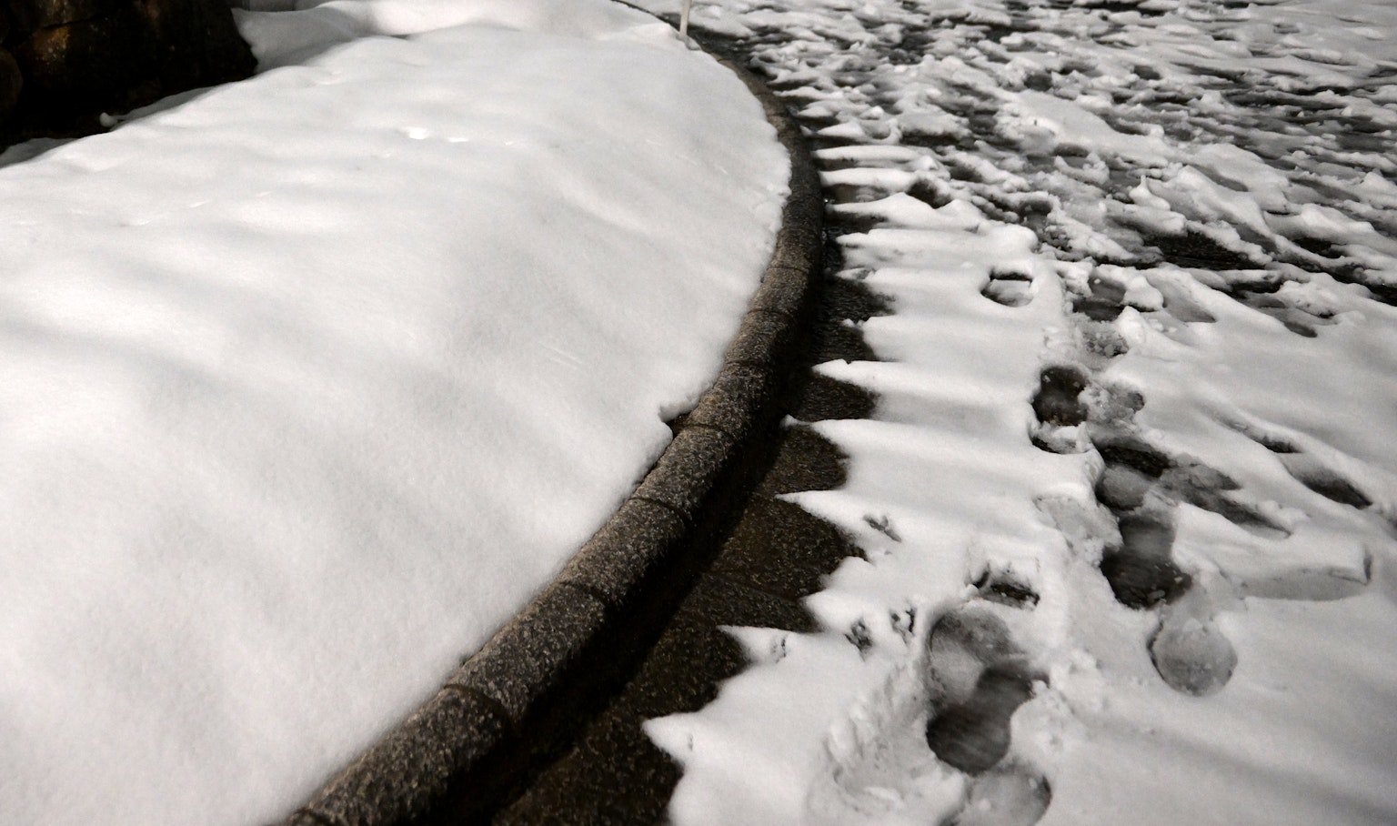 Impronte nella neve su un marciapiede curvo coperto di neve
