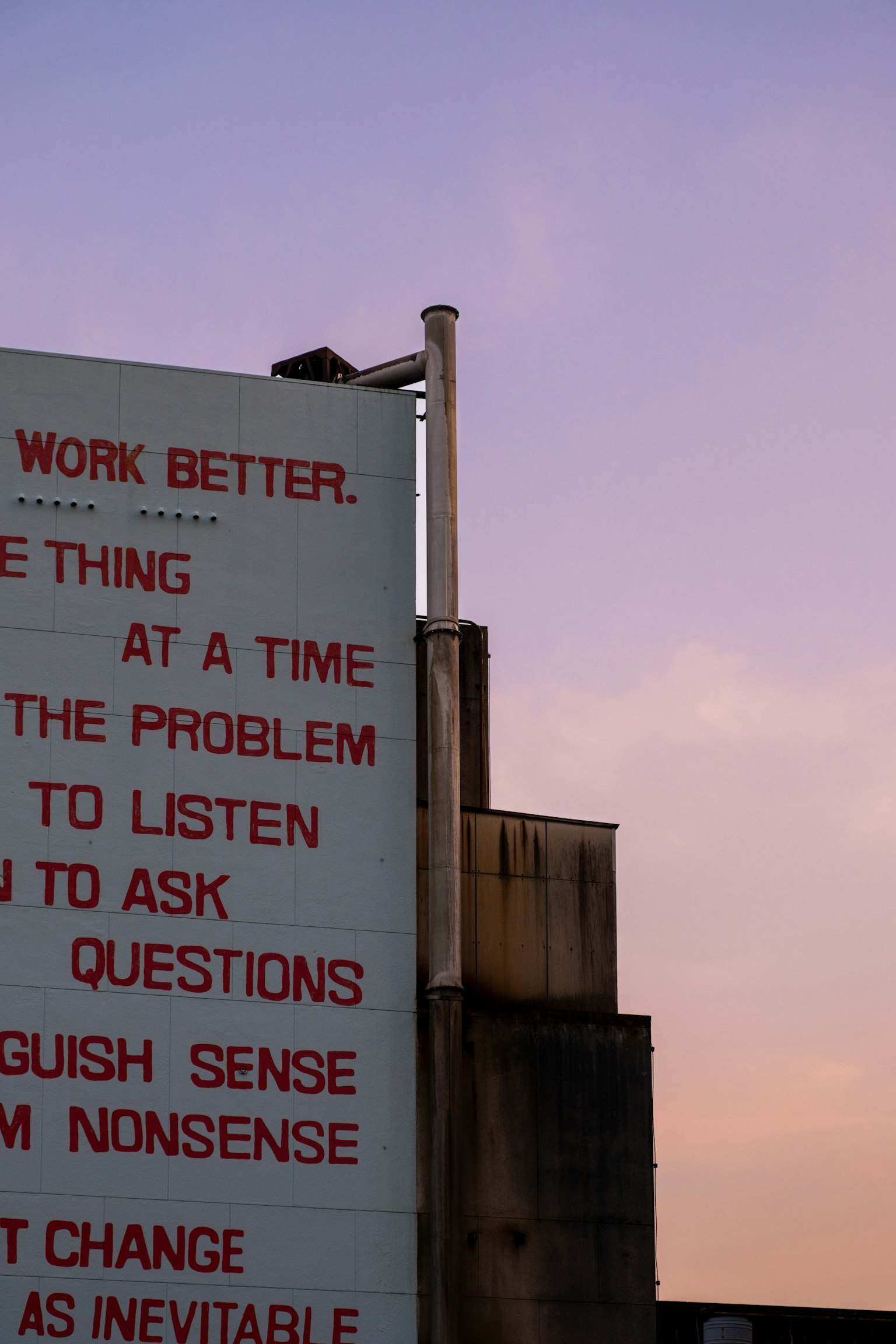 赤い文字で書かれたメッセージがあるビルの壁と夕焼けの空