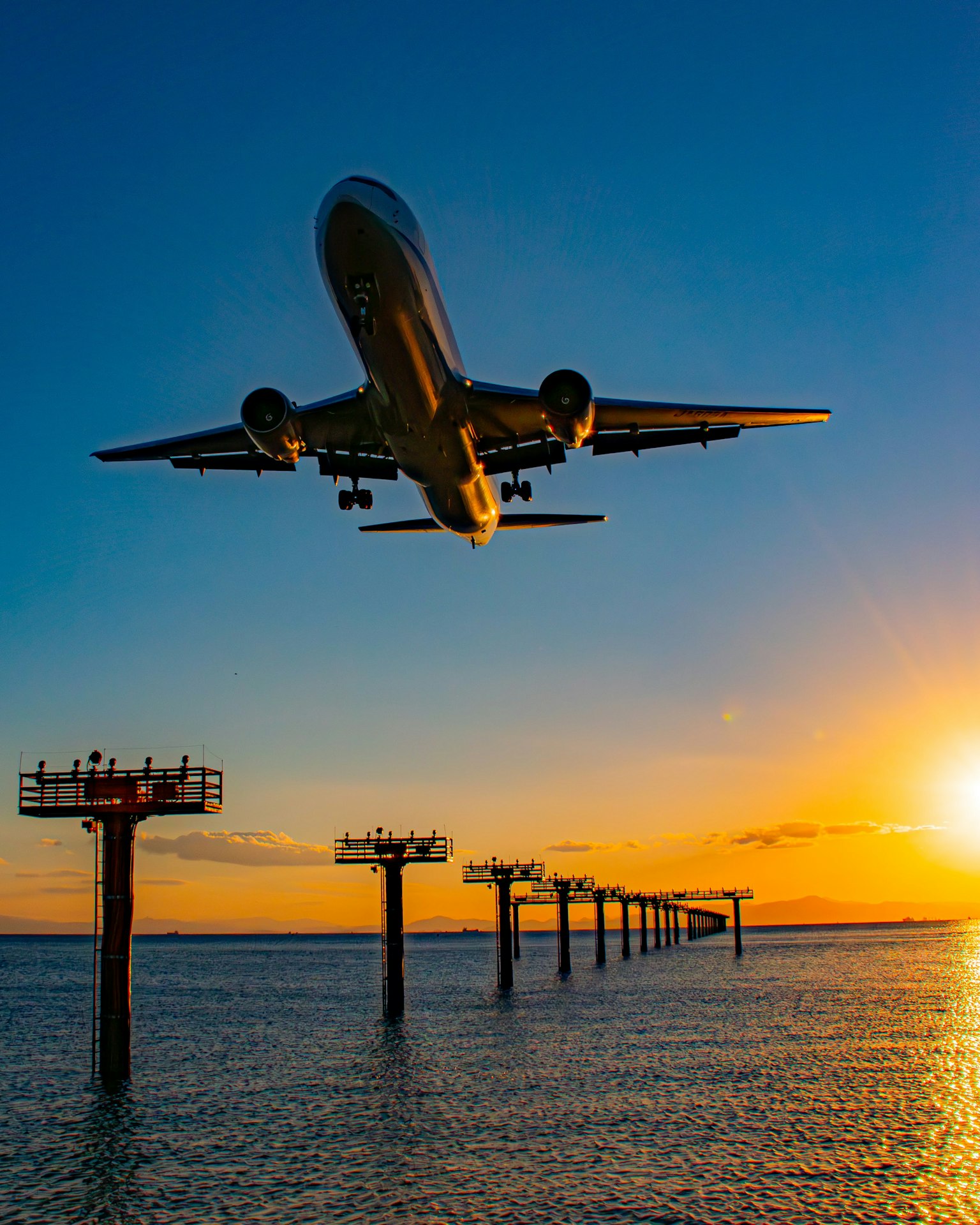 해질녘 물 위의 부두를 비행하는 비행기