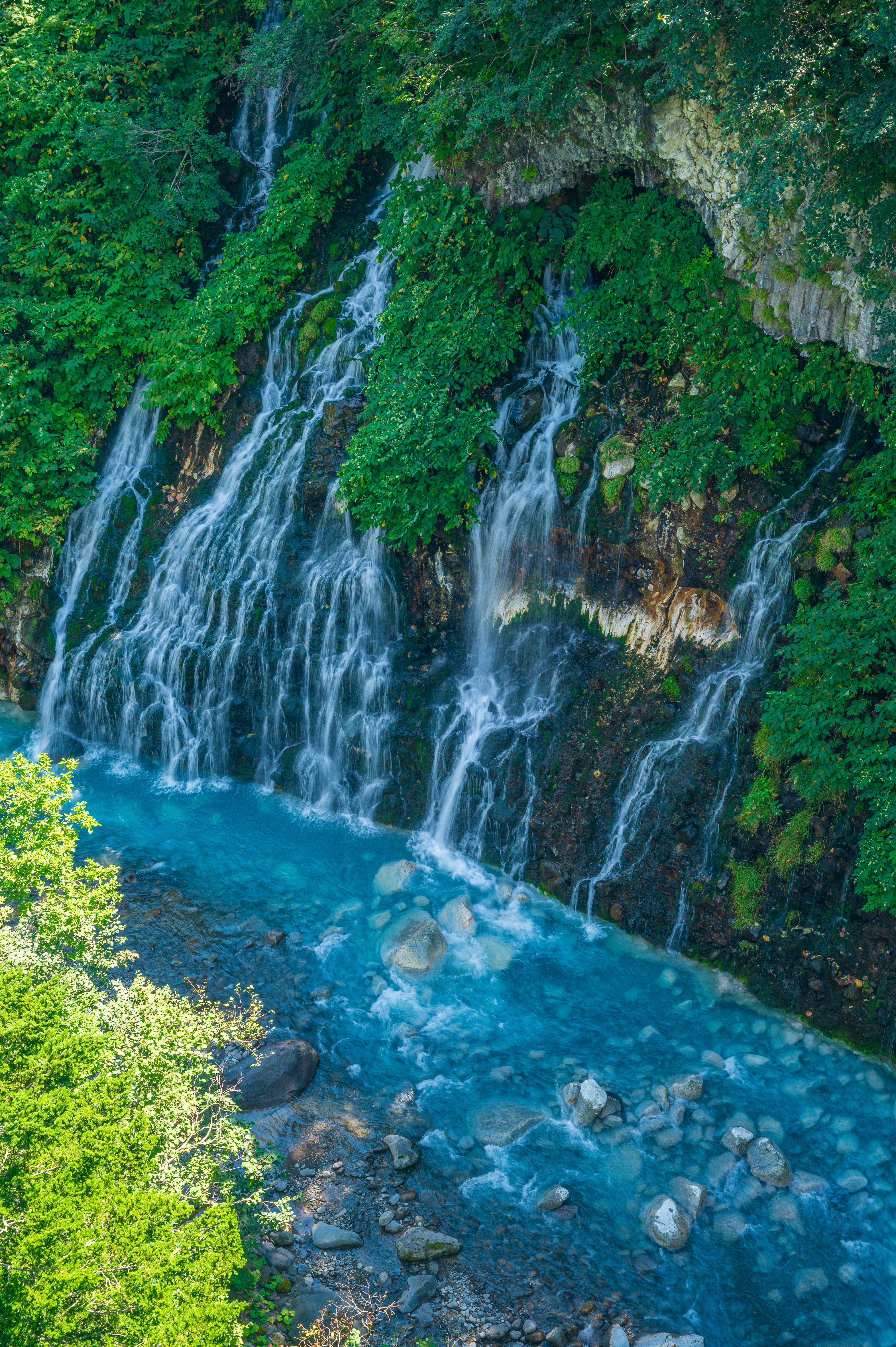 A beautiful waterfall surrounded by lush greenery and turquoise water