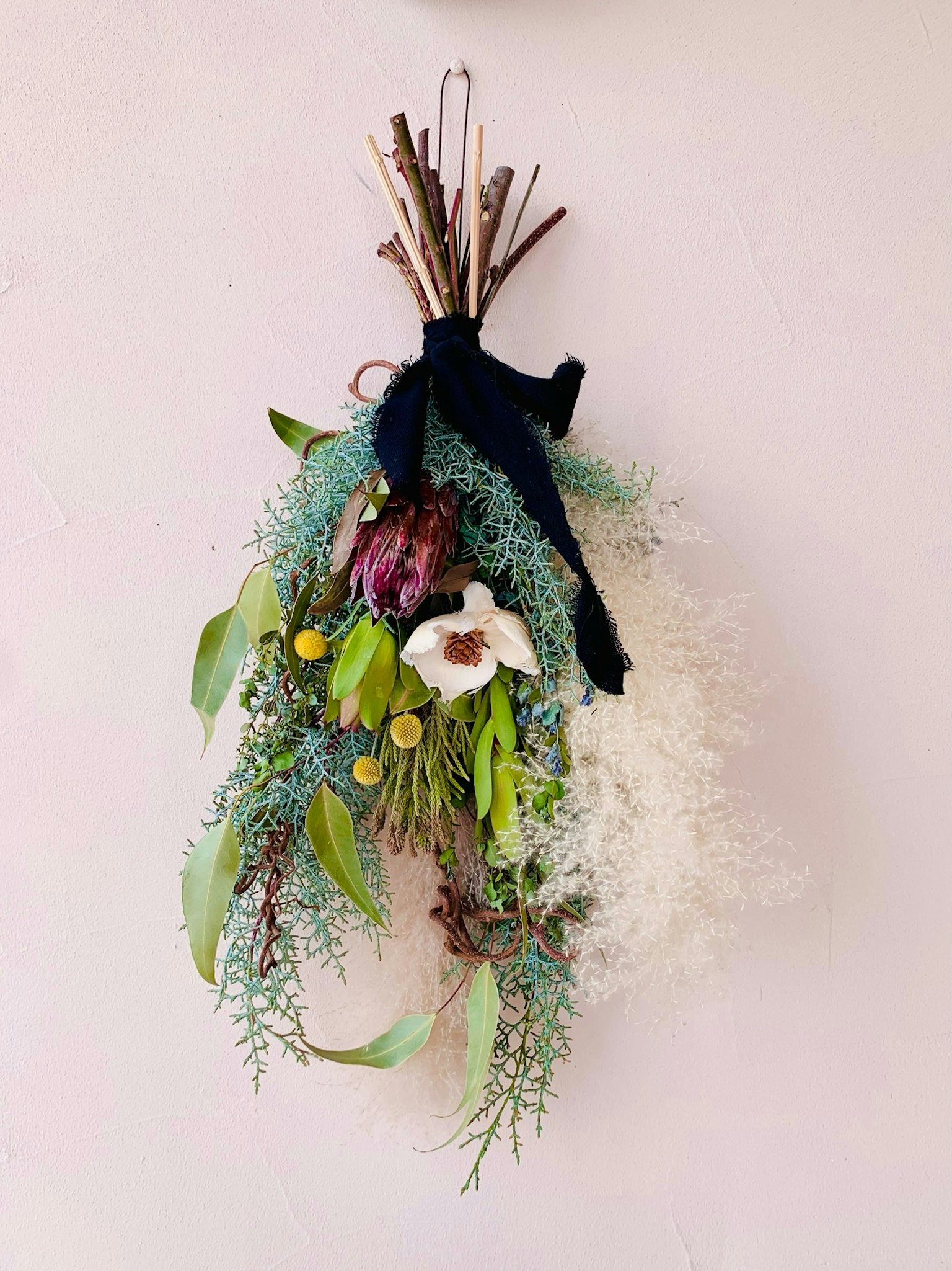 Une belle composition de fleurs séchées et de feuillage suspendue de manière décorative