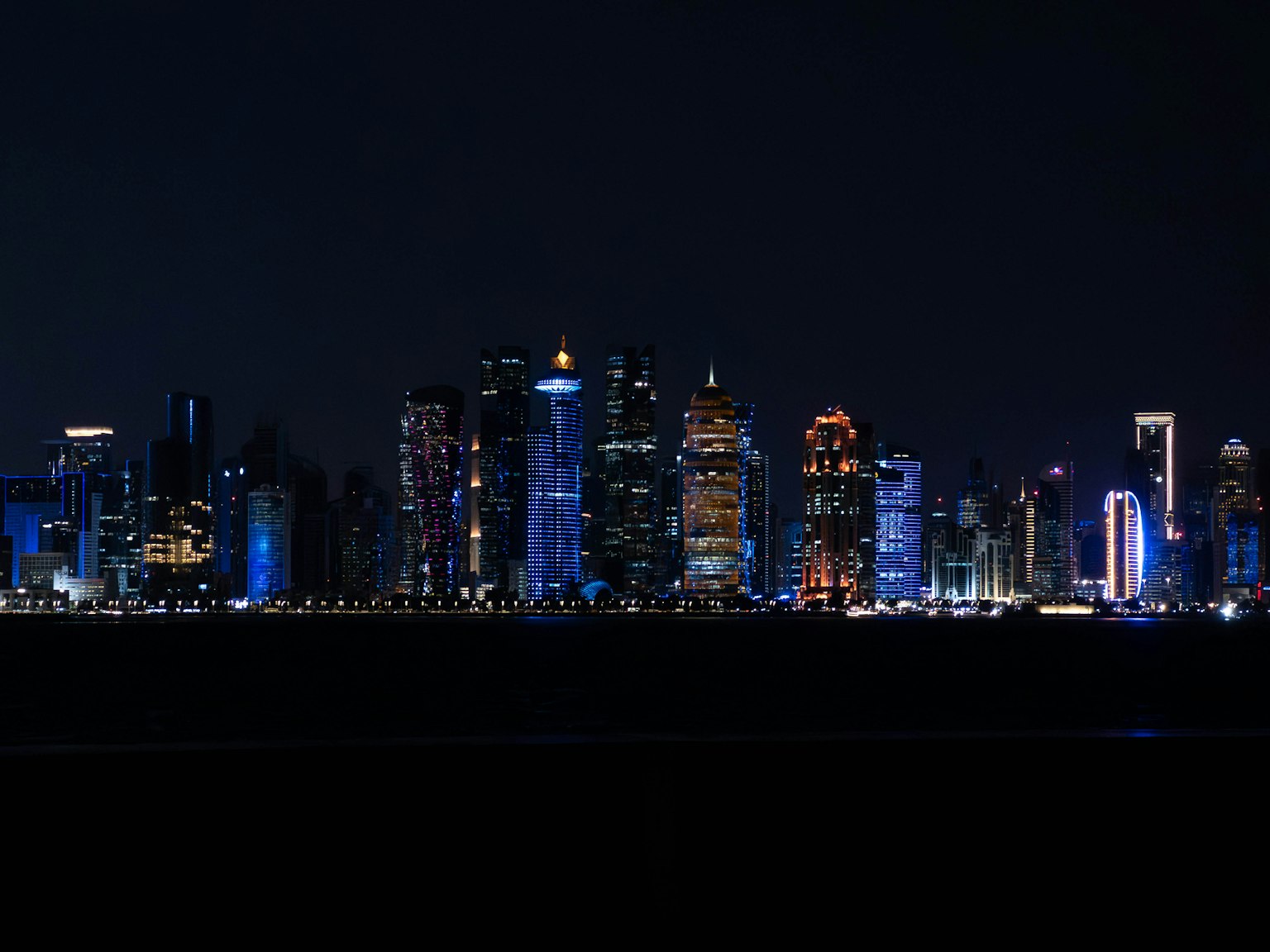 Horizonte de la ciudad de noche iluminado con luces azules y naranjas