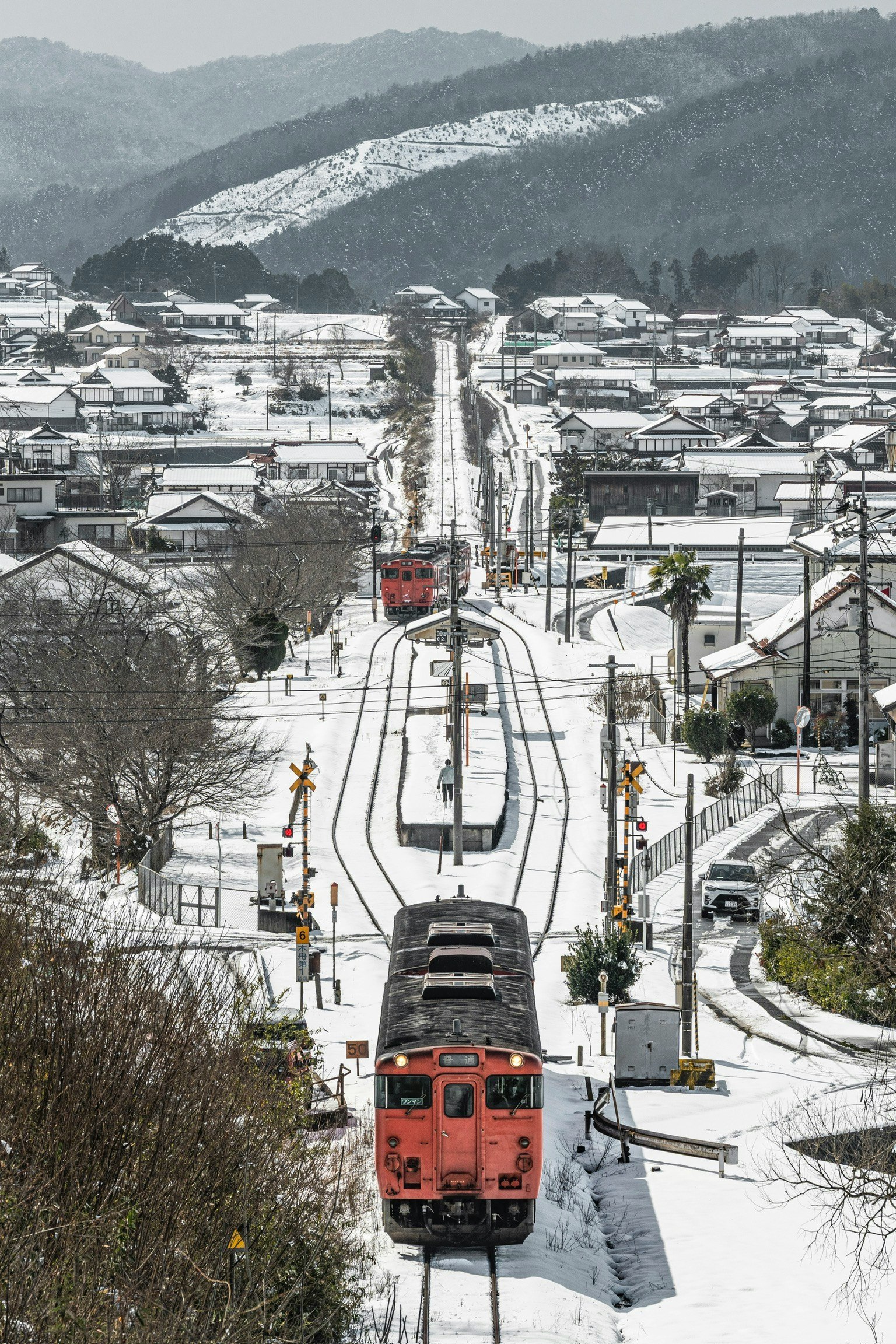 雪の芸備線を走る列車と冬の沿線の街並み