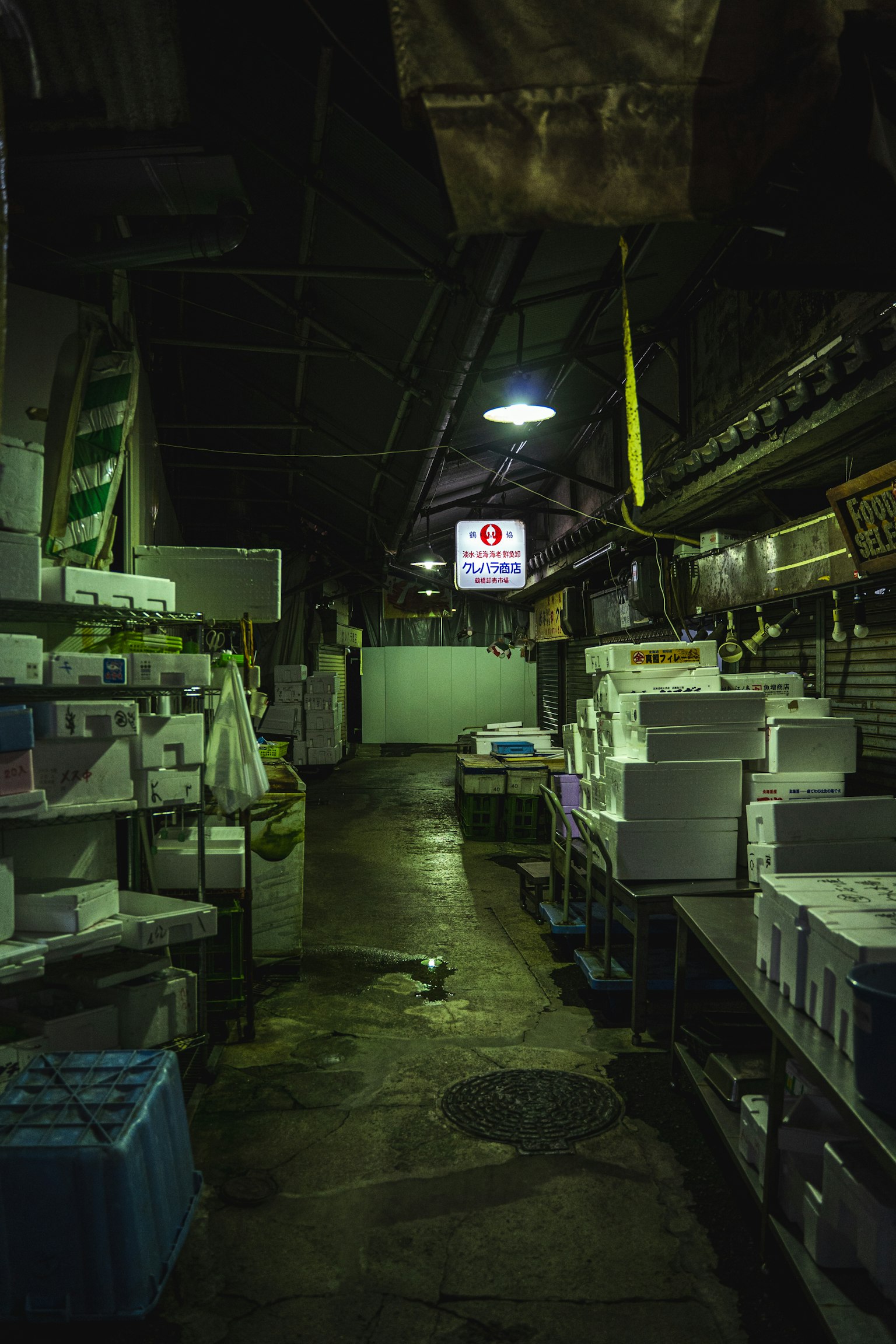 Interior de un mercado poco iluminado con pilas de cajas y paquetes