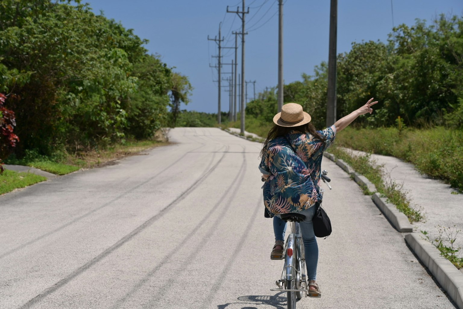 Una mujer montando una bicicleta señalando hacia el horizonte