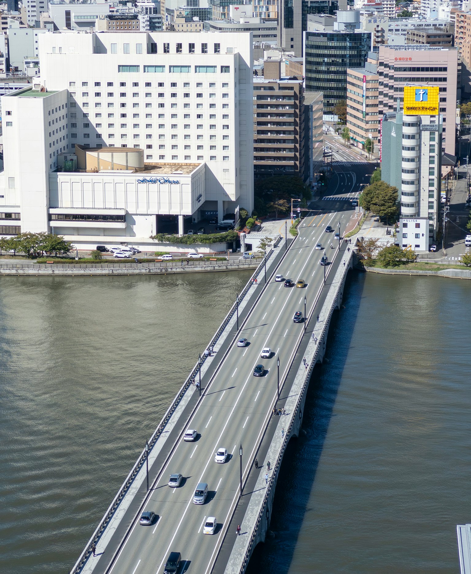 สะพานข้ามแม่น้ำที่มีรถยนต์และอาคารในเมืองด้านหลัง