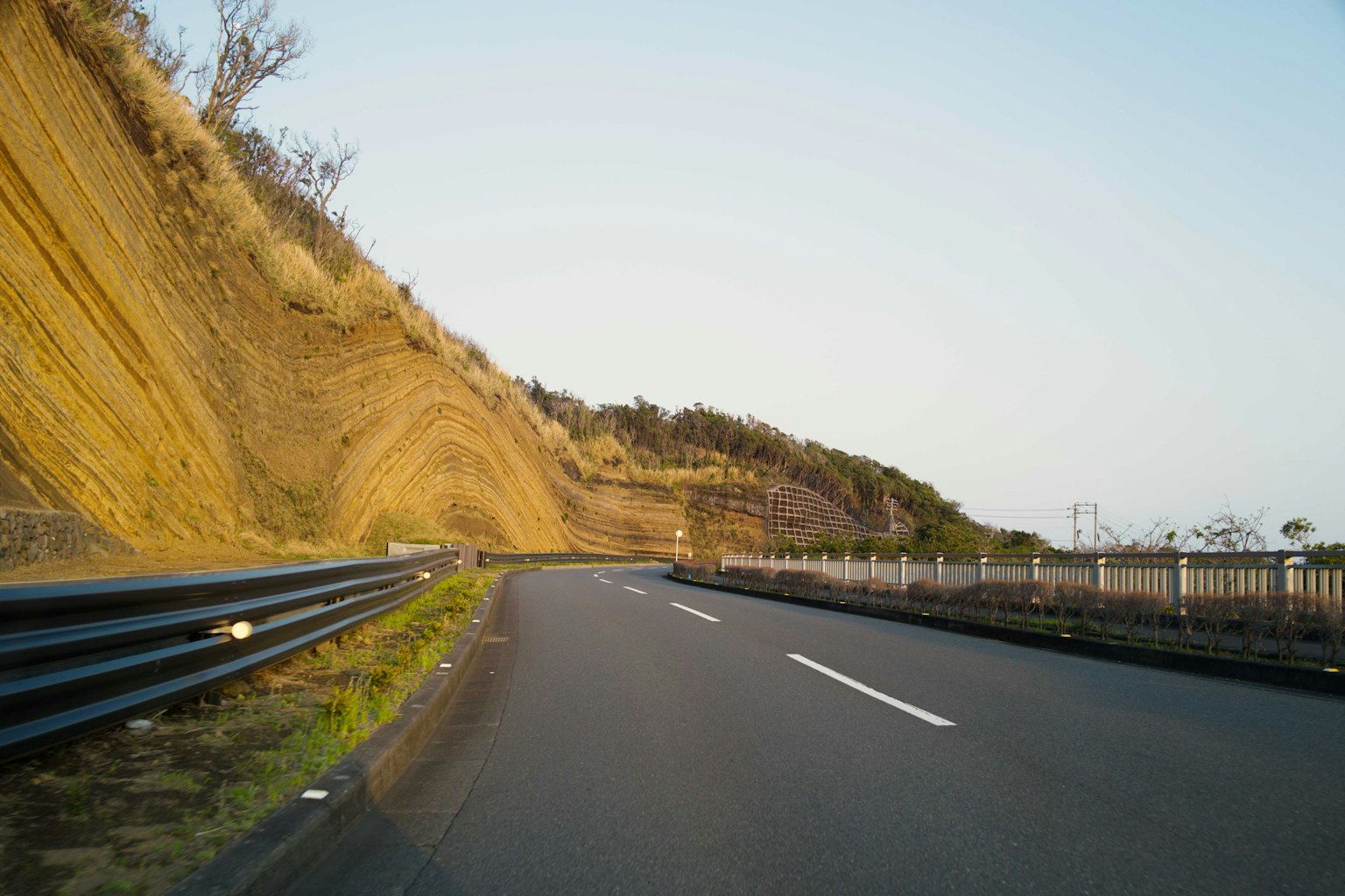 Carretera curva con una colina y cielo azul claro