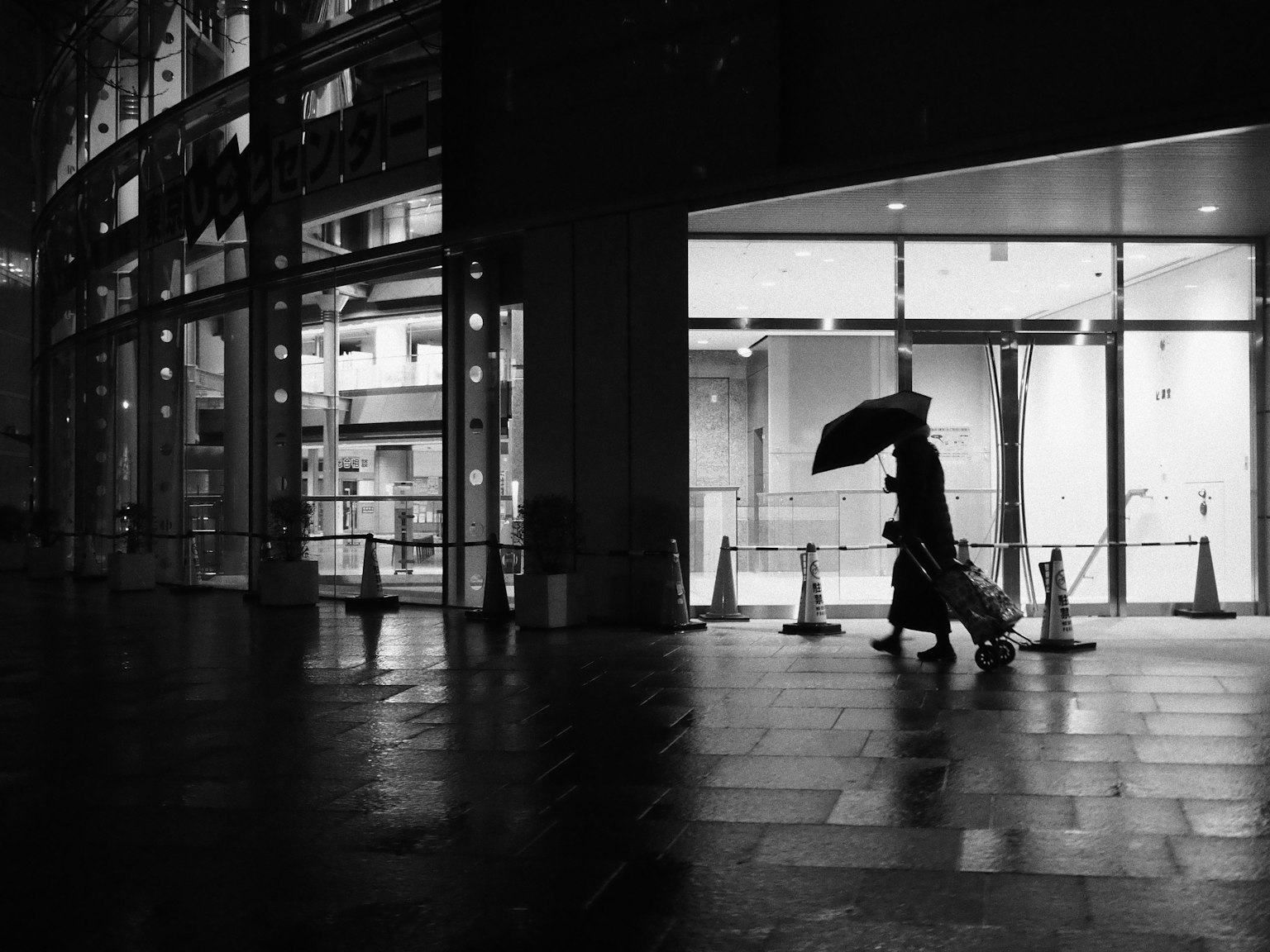 夜の街で傘を持った人が歩いているシルエット