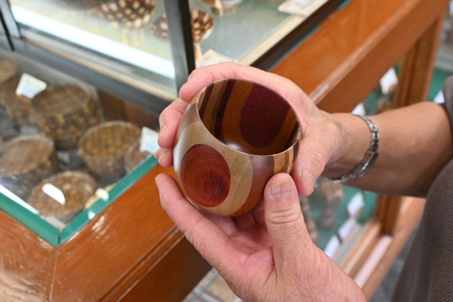 Une tasse en bois magnifiquement conçue tenue dans des mains avec des motifs en bois colorés