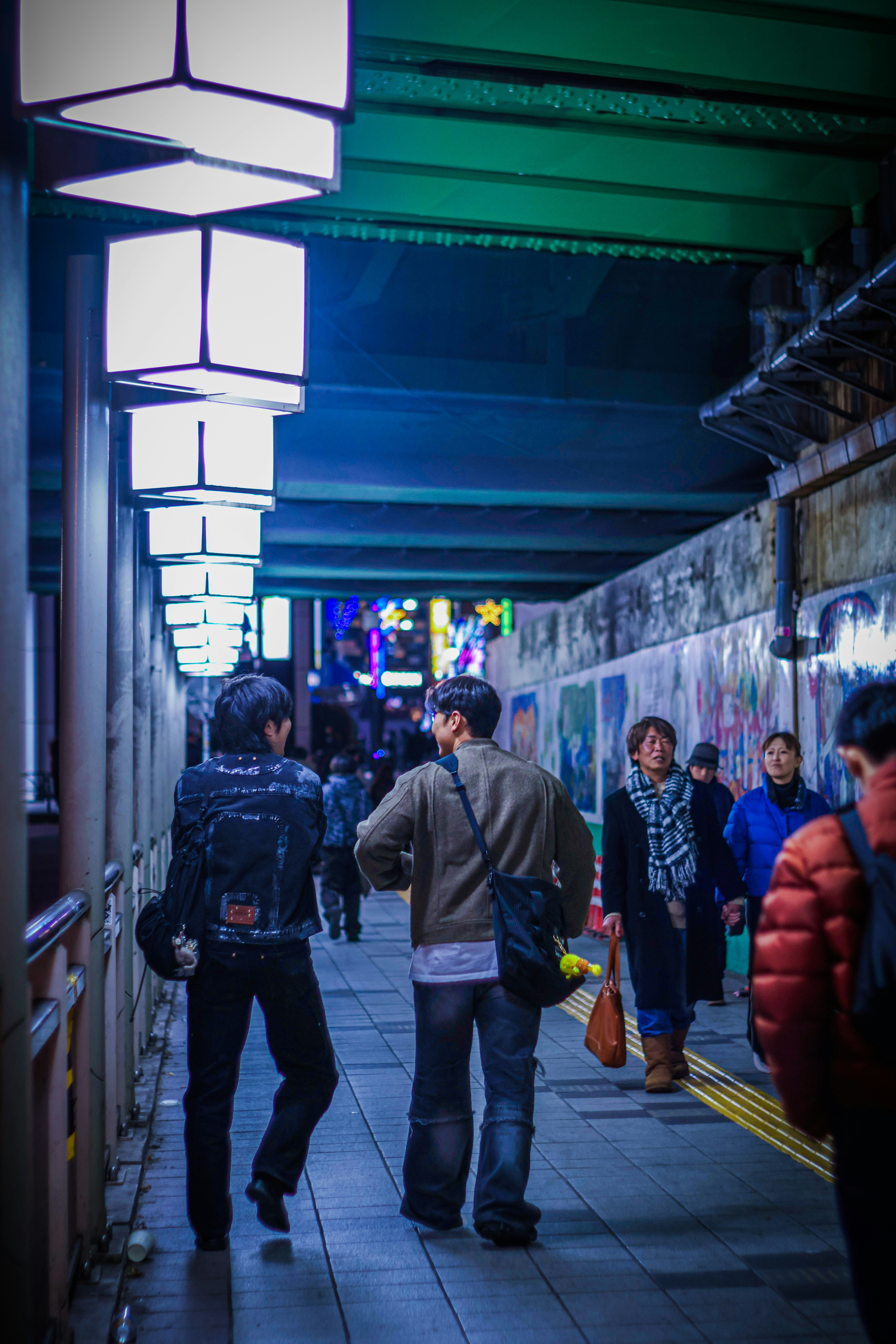 壁の落書きがある路地の夜の通りを歩く人々