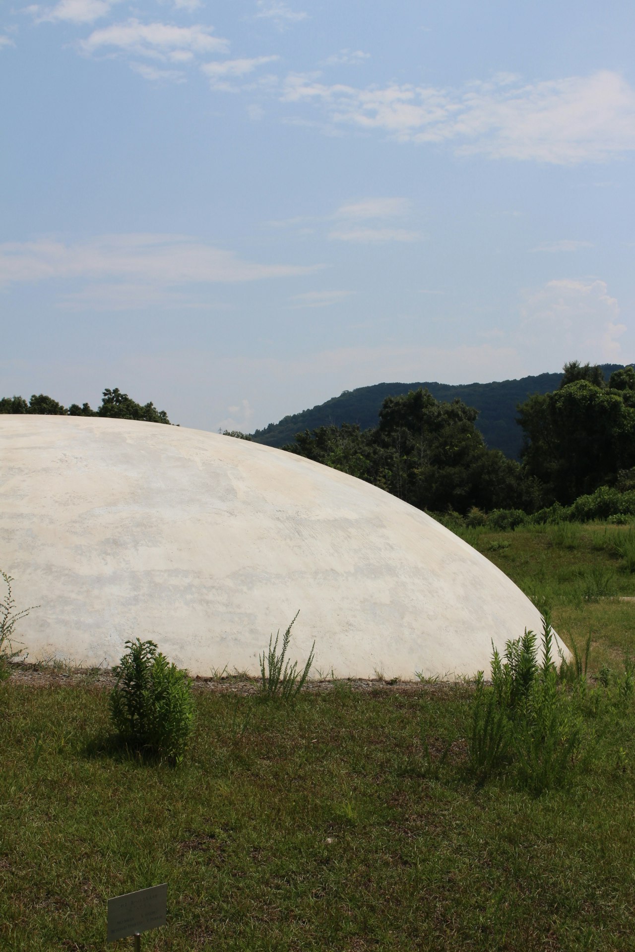 丘の上の大きな白いドーム状建物と緑の草地