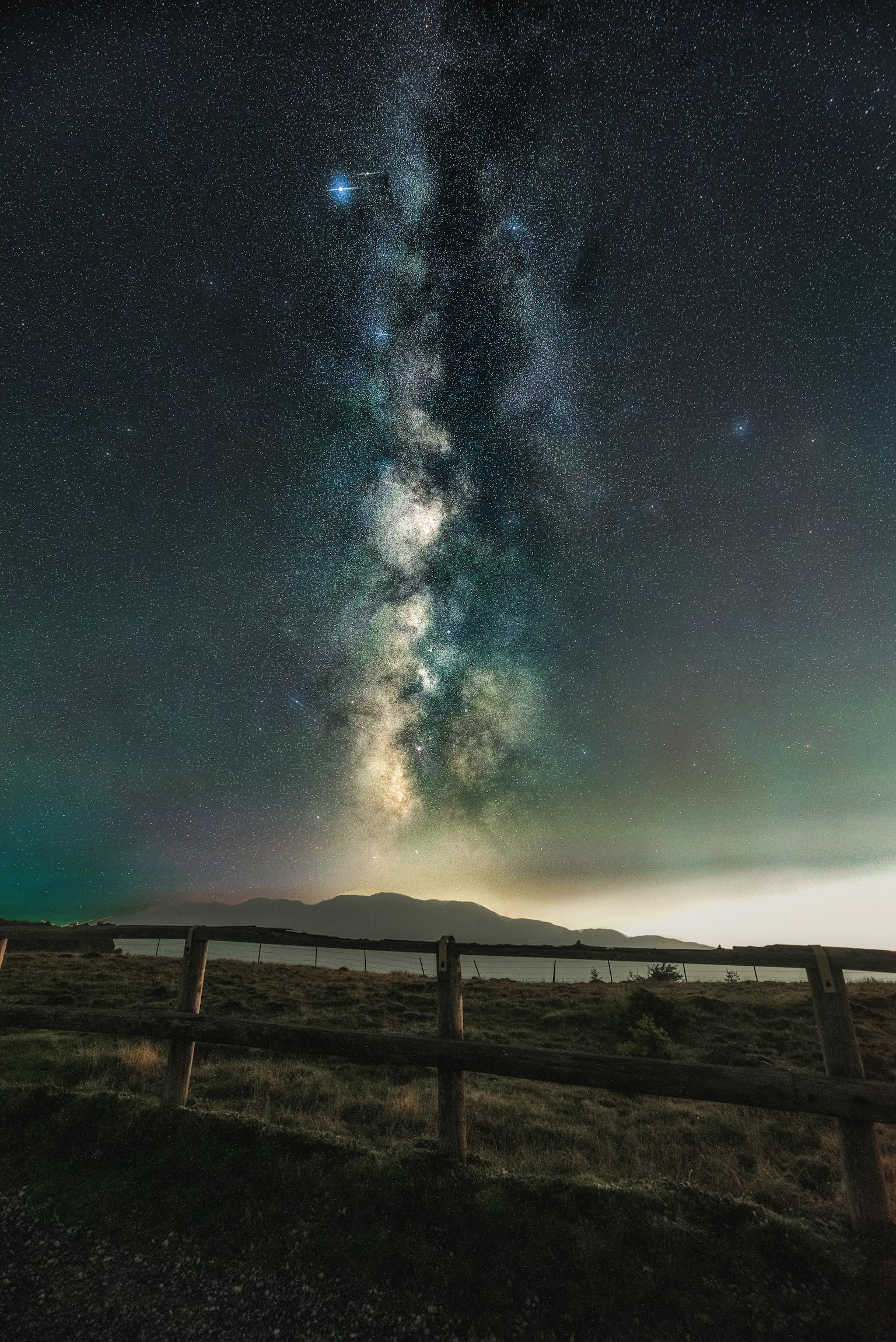 Milky Way galaxy view above mountains with wooden fence