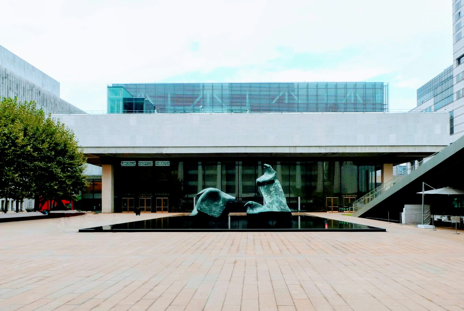 Sculptures en bronze abstraites devant un bâtiment moderne avec une terrasse en bois