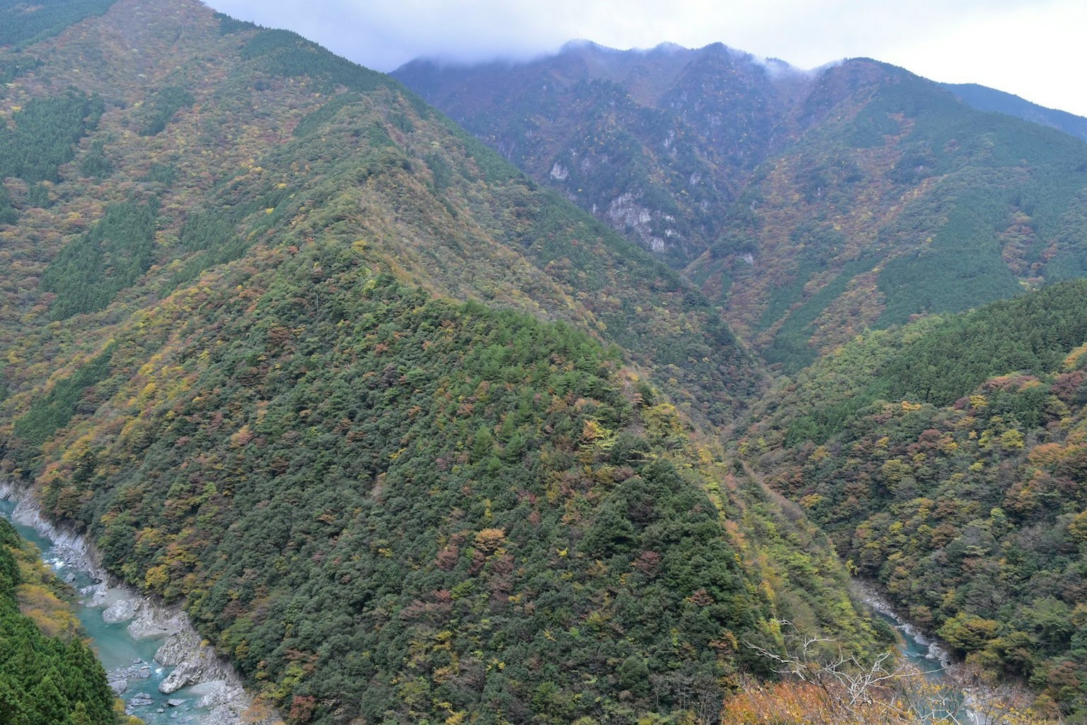 Gunung hijau subur dengan sungai mengalir di lembah