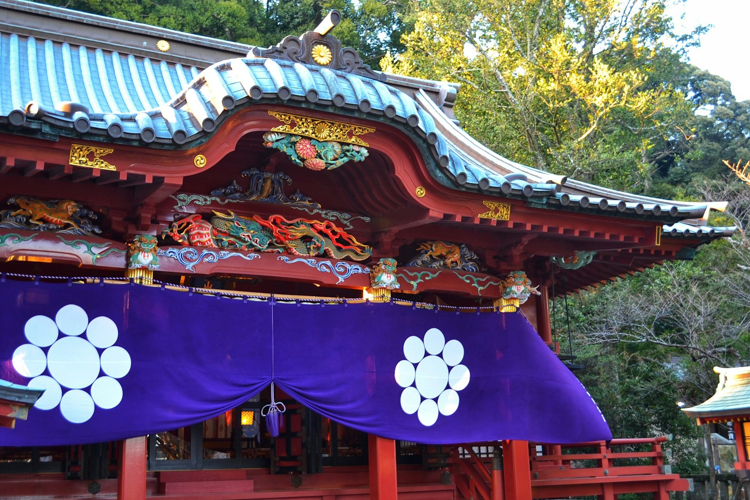 神社的精美屋顶和带有白色花卉图案的紫色幕帘