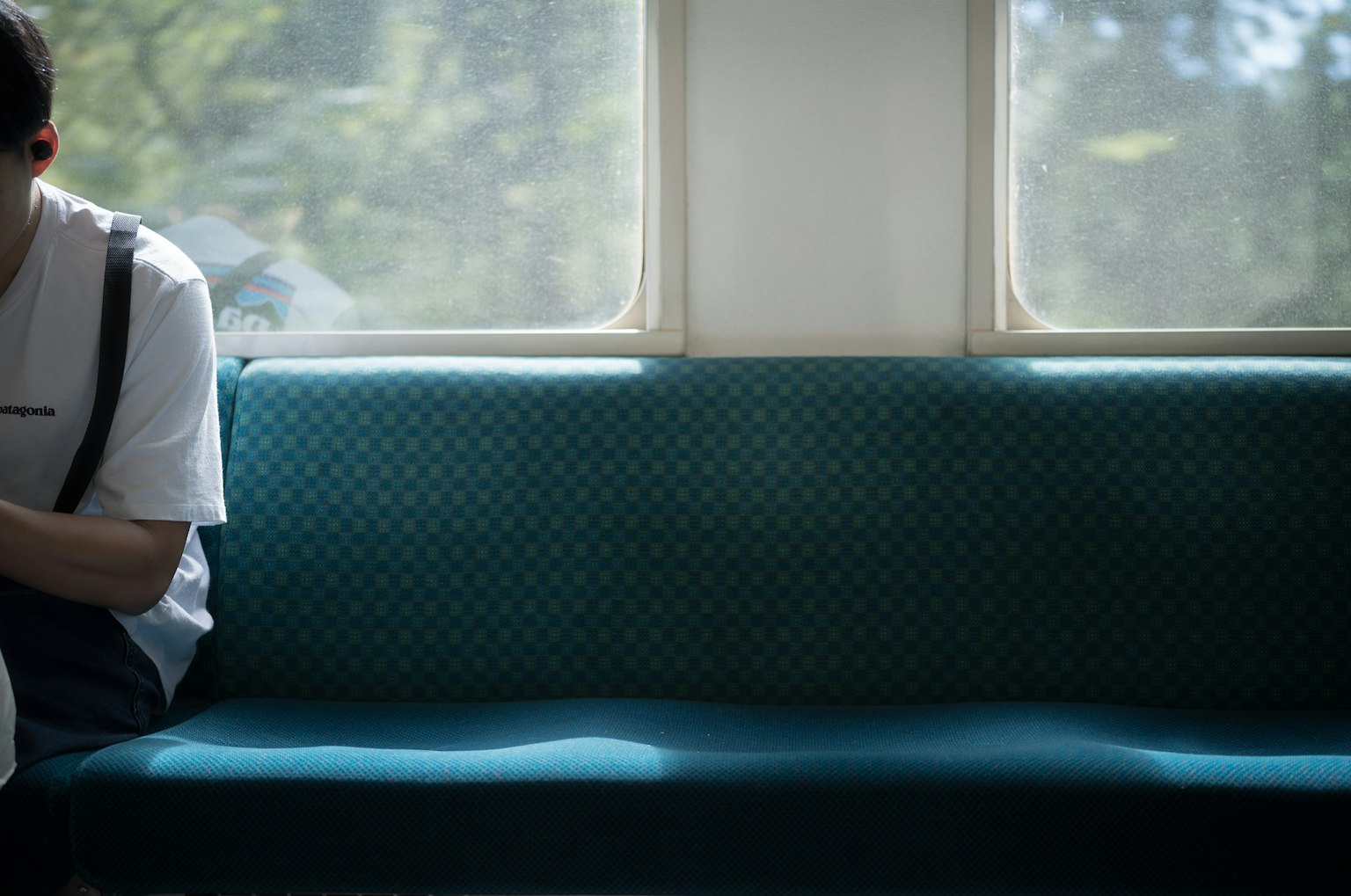 Man sitting on a blue sofa with sunlight filtering through the window