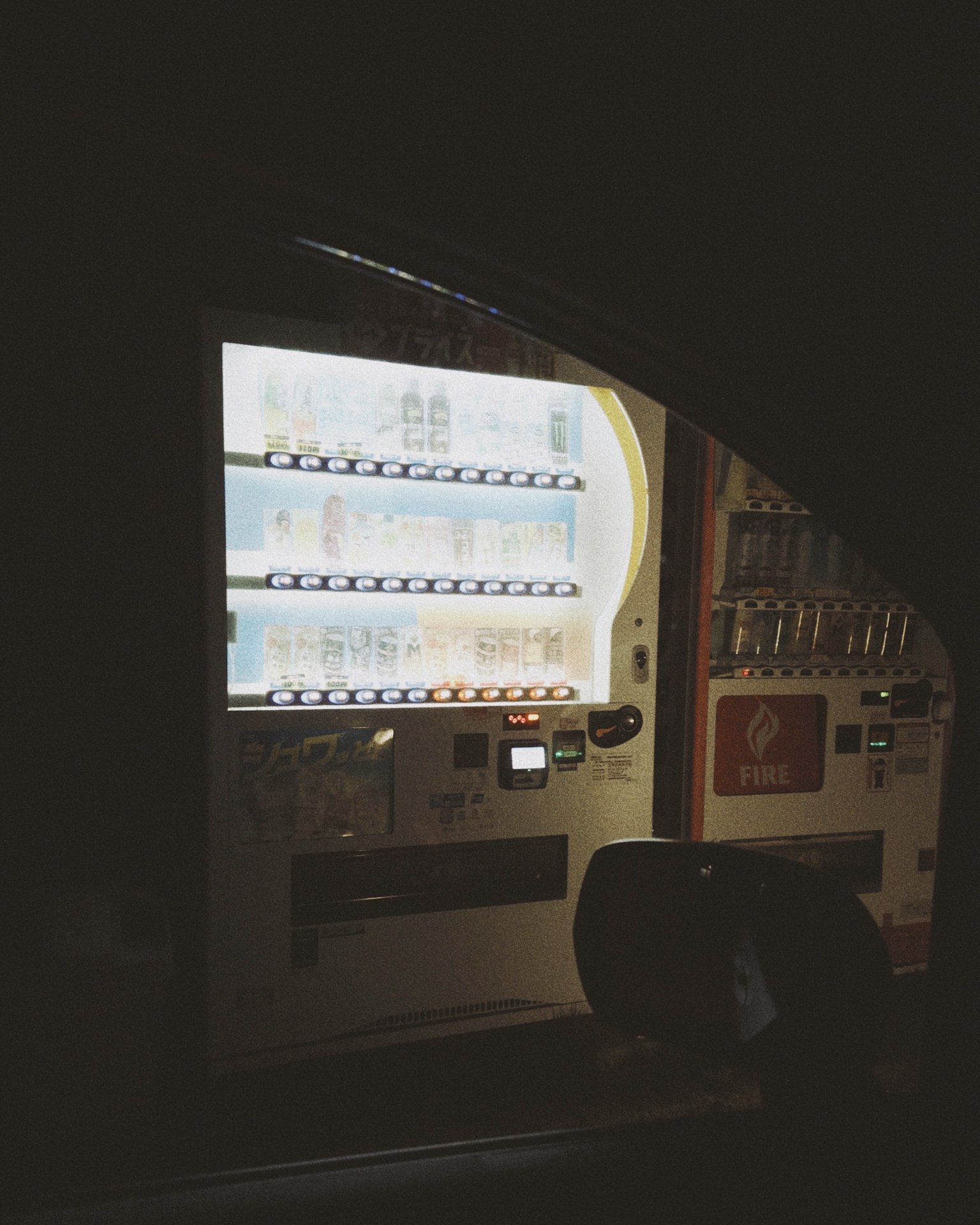 暗い背景に明るい自動販売機が映る
