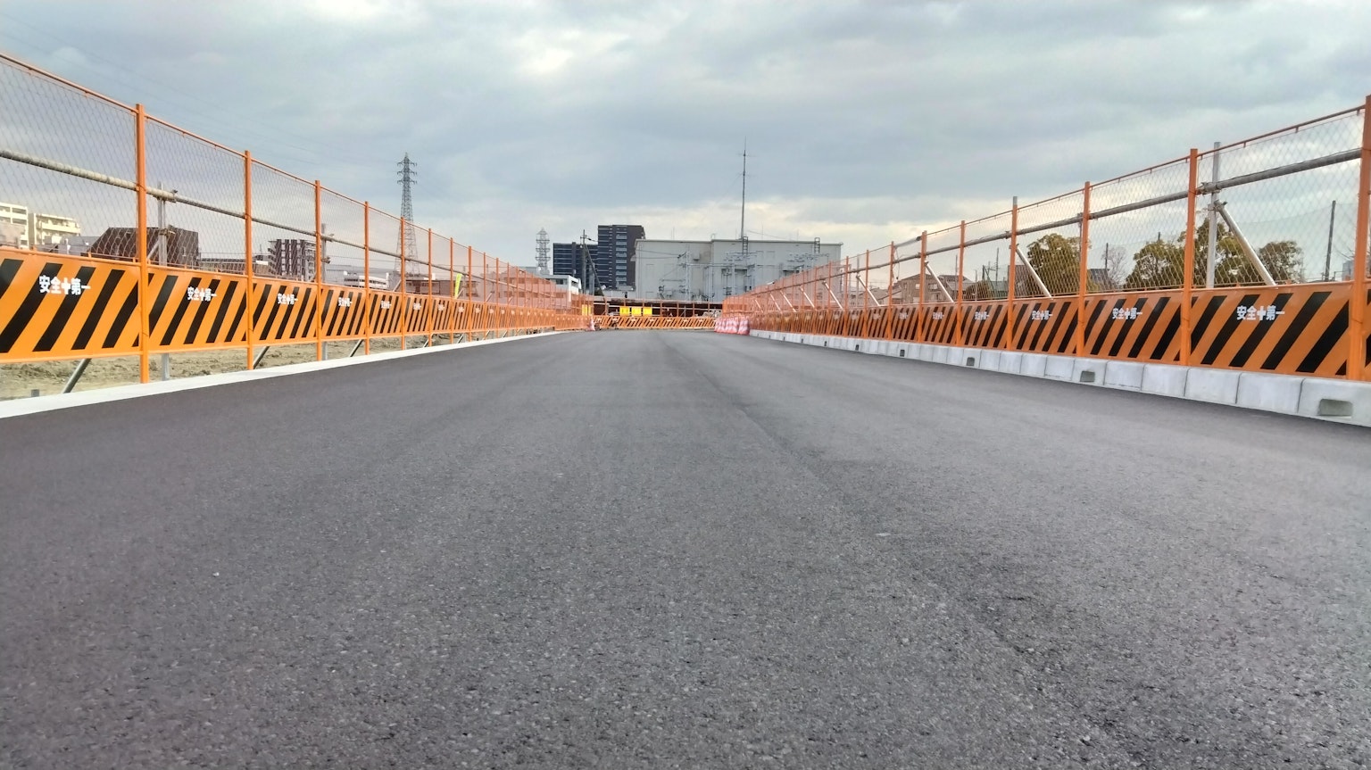 ทิวทัศน์ของถนนยางมะตอยใหม่พร้อมรั้วกั้นสีส้มบนสะพาน