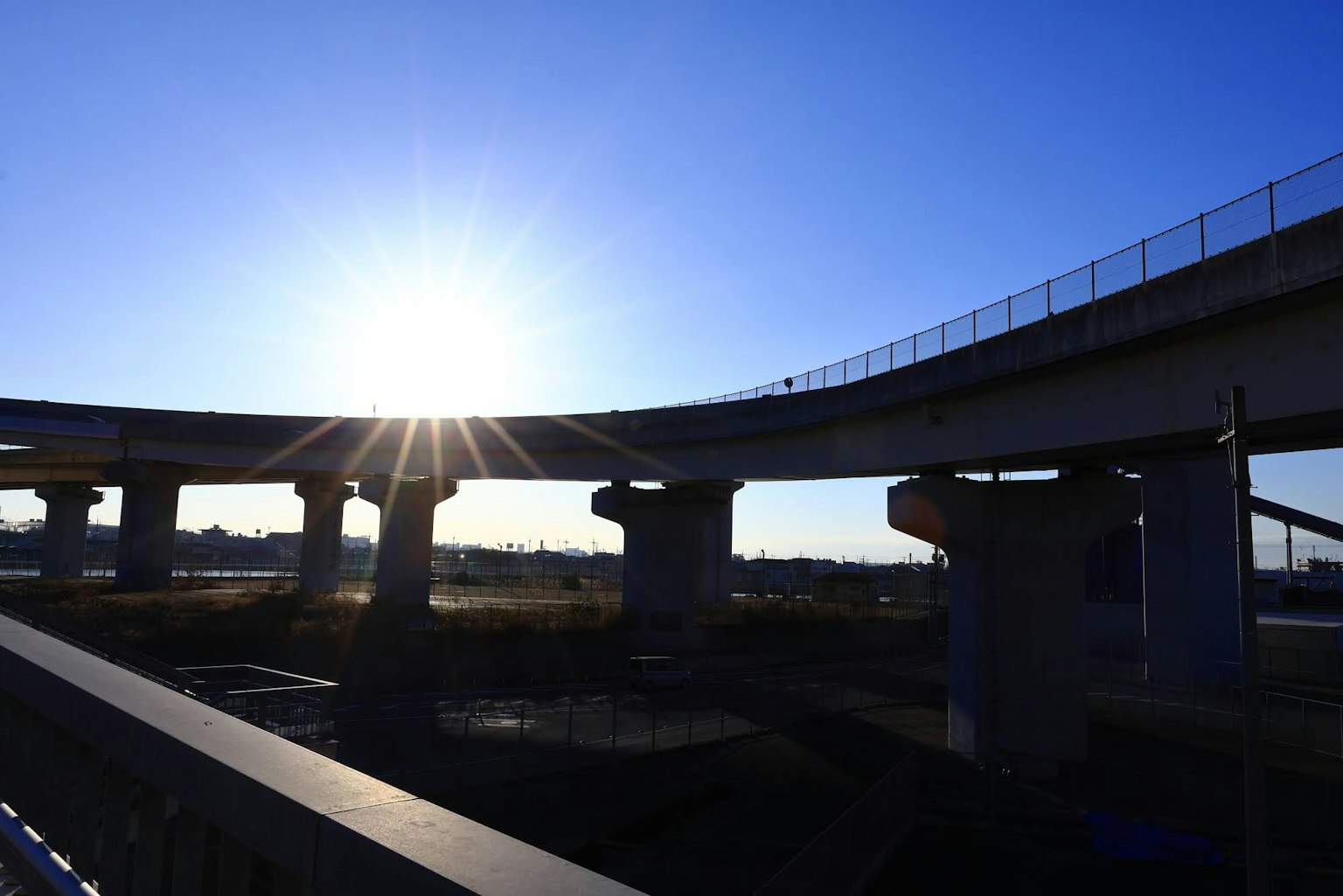 Siluet jembatan tinggi di bawah matahari terbenam