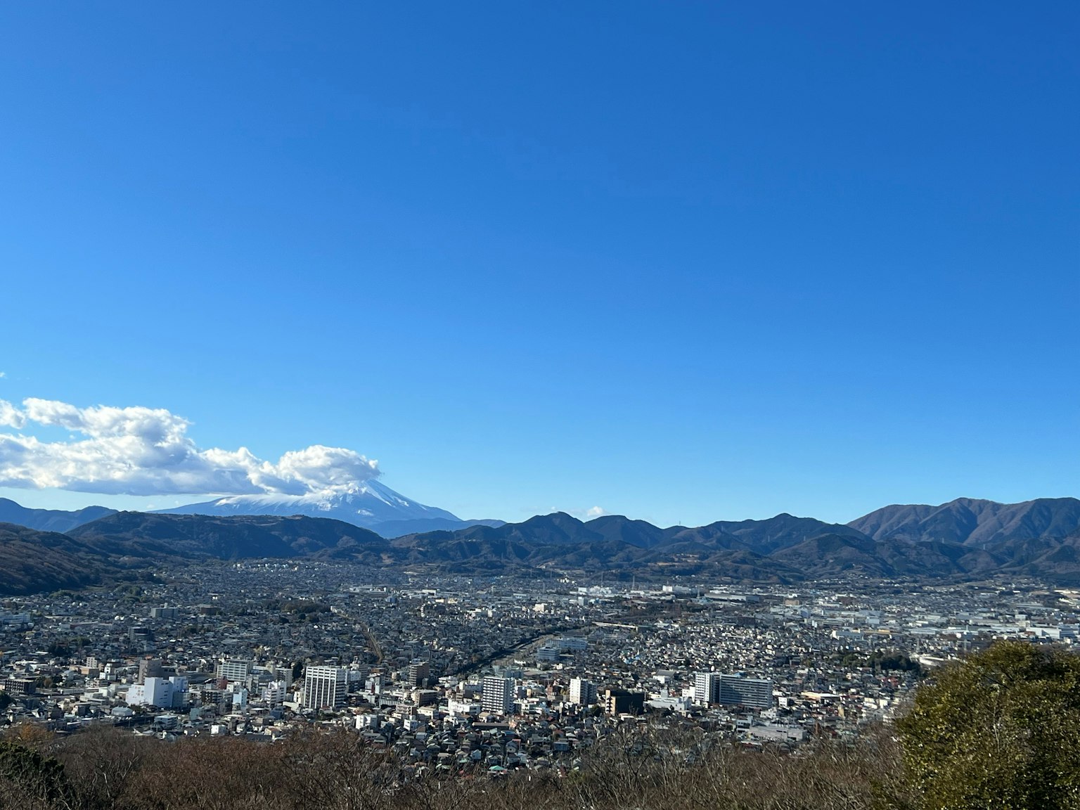Vista panoramica di una città con il monte Fuji sullo sfondo cielo blu e montagne
