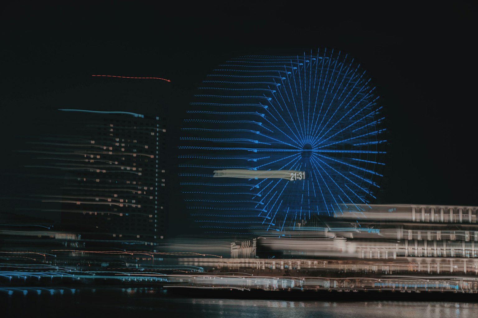 模糊的夜间城市天际线图像，带有蓝色摩天轮