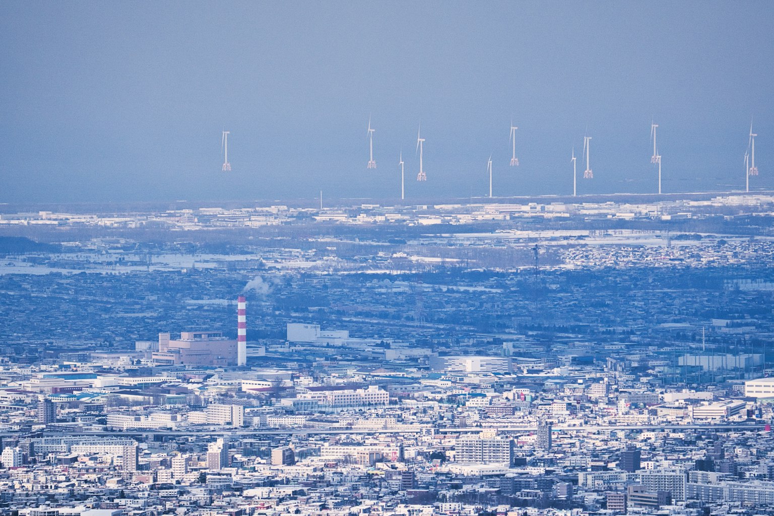 Una vista della città sotto un cielo blu con turbine eoliche in lontananza