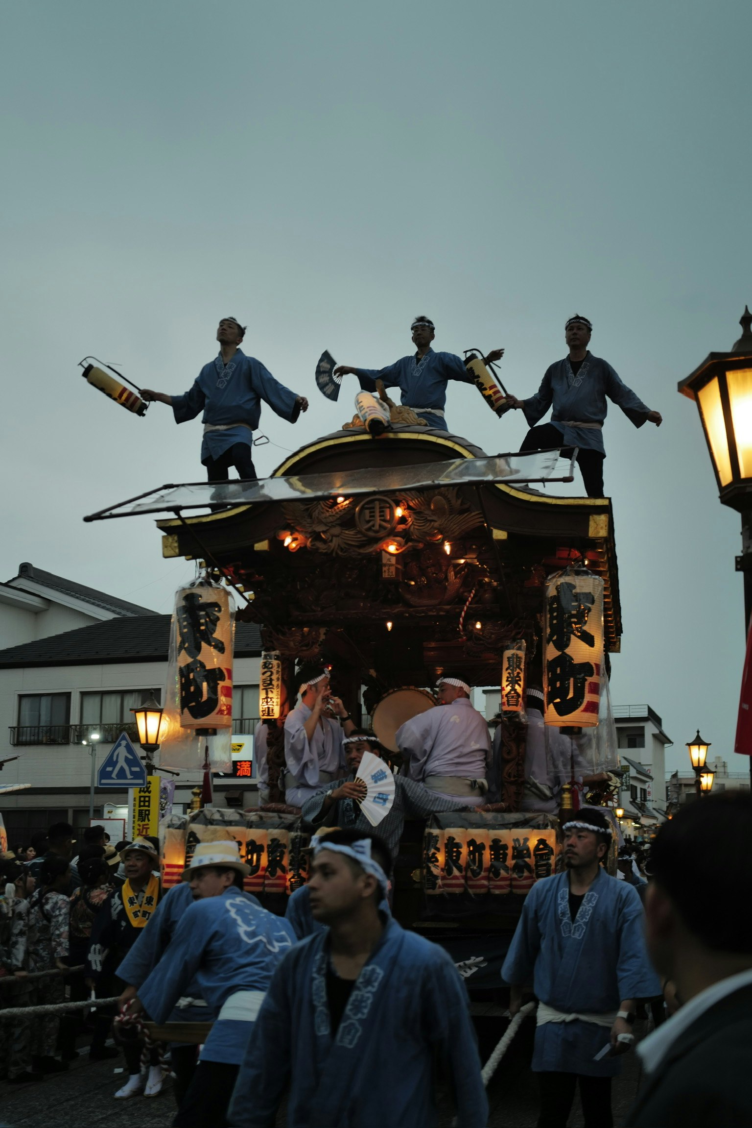 山車の上で踊る人々と提灯のある祭りの夜の街並み