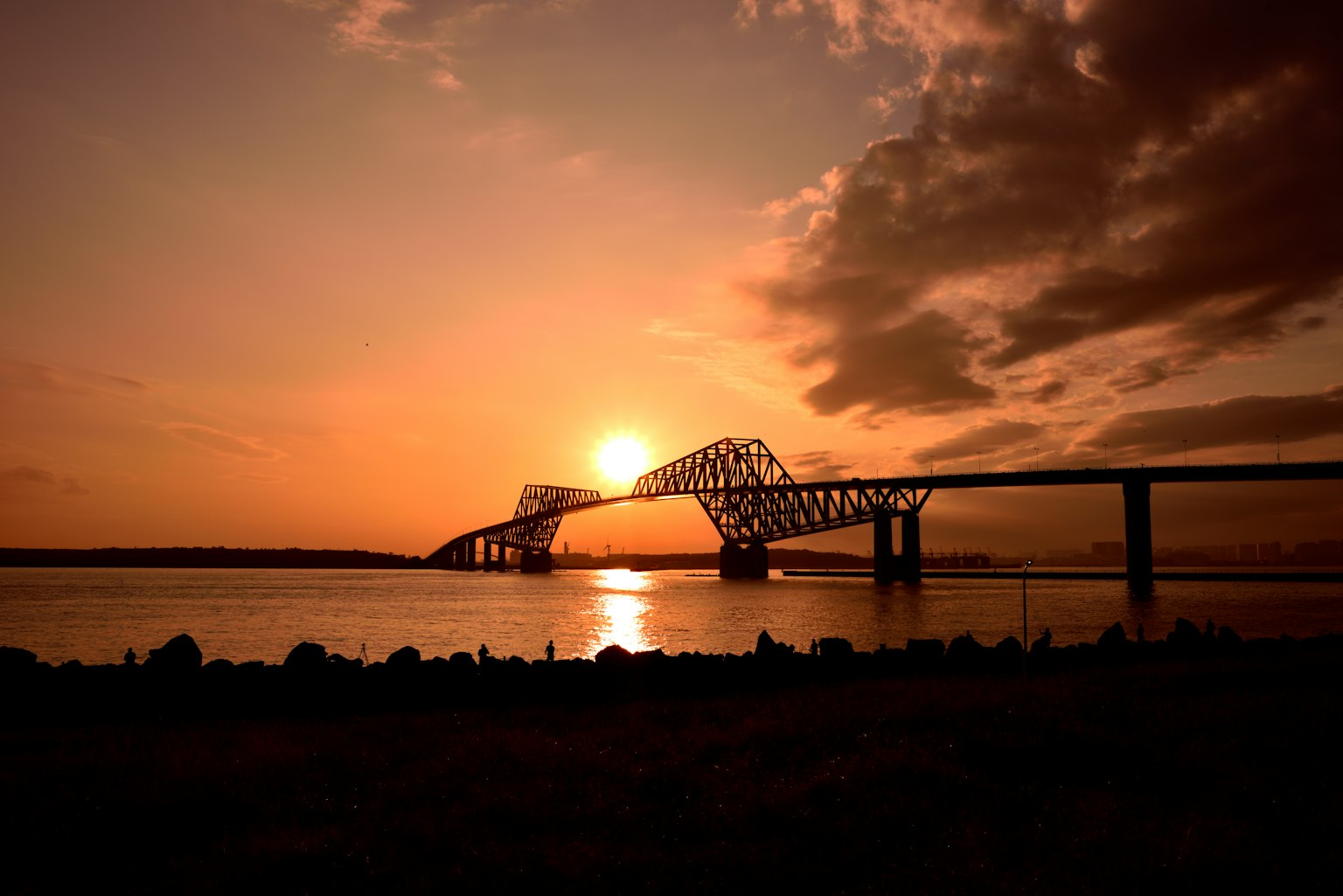 Silhouette einer Brücke gegen den Sonnenuntergang mit Reflexionen im Wasser