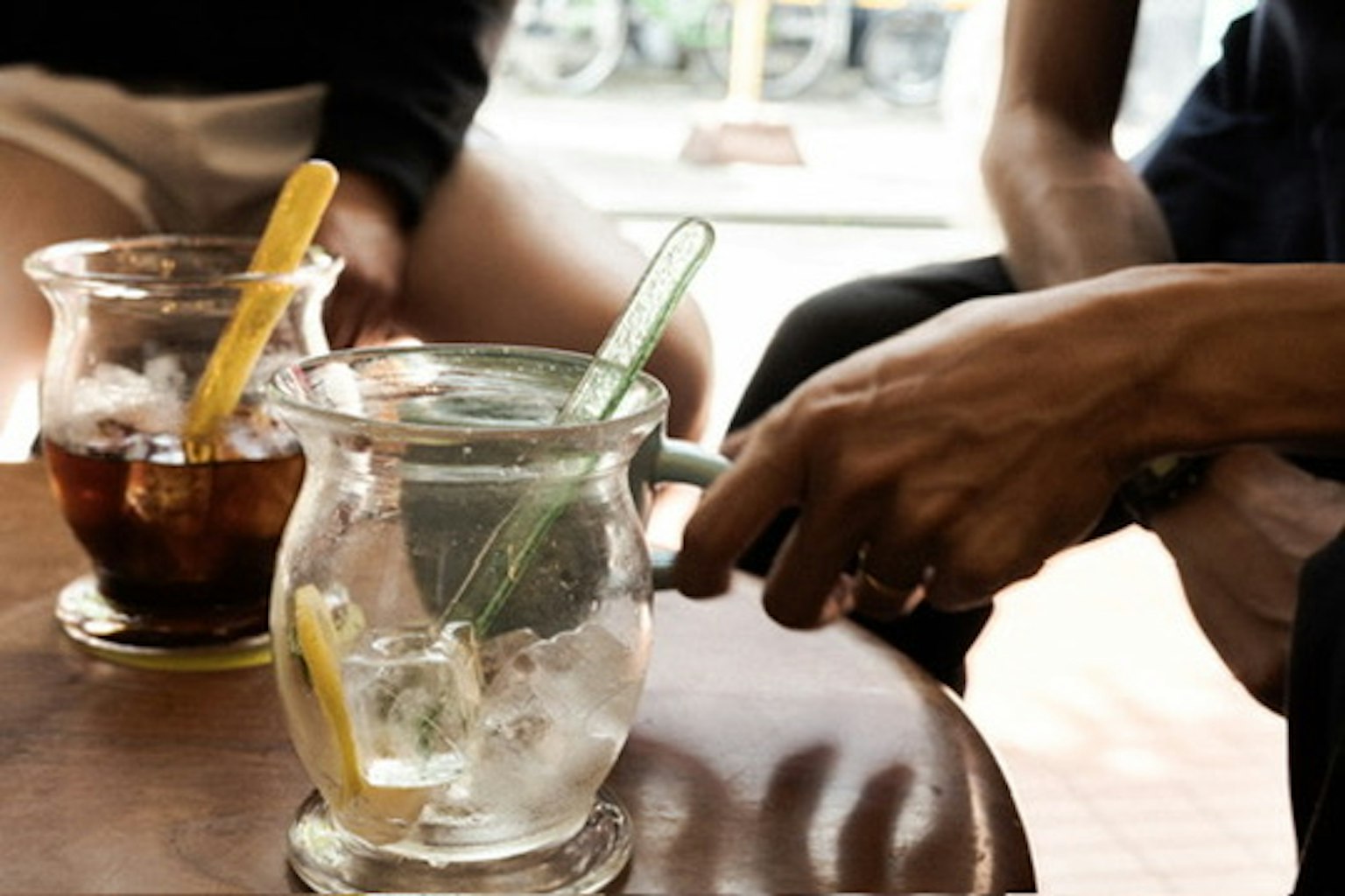 Close-up of drinks on a table featuring a transparent glass with ice and lemon