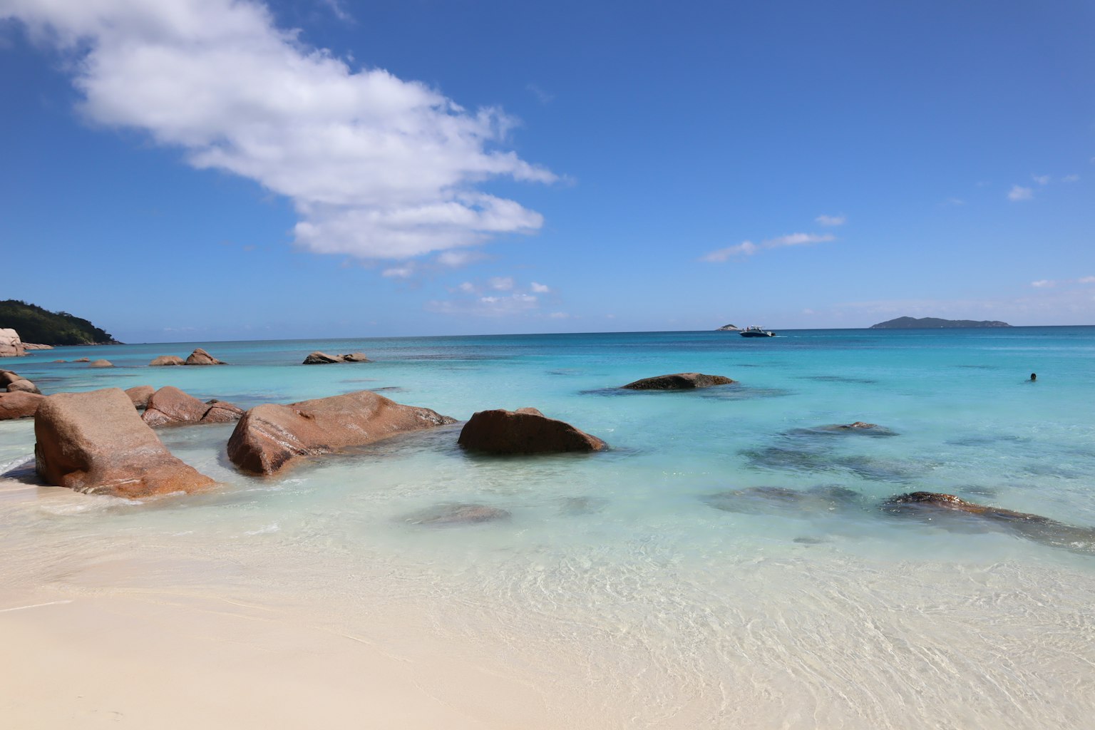 Scenic beach with turquoise water and white sand featuring scattered rocks
