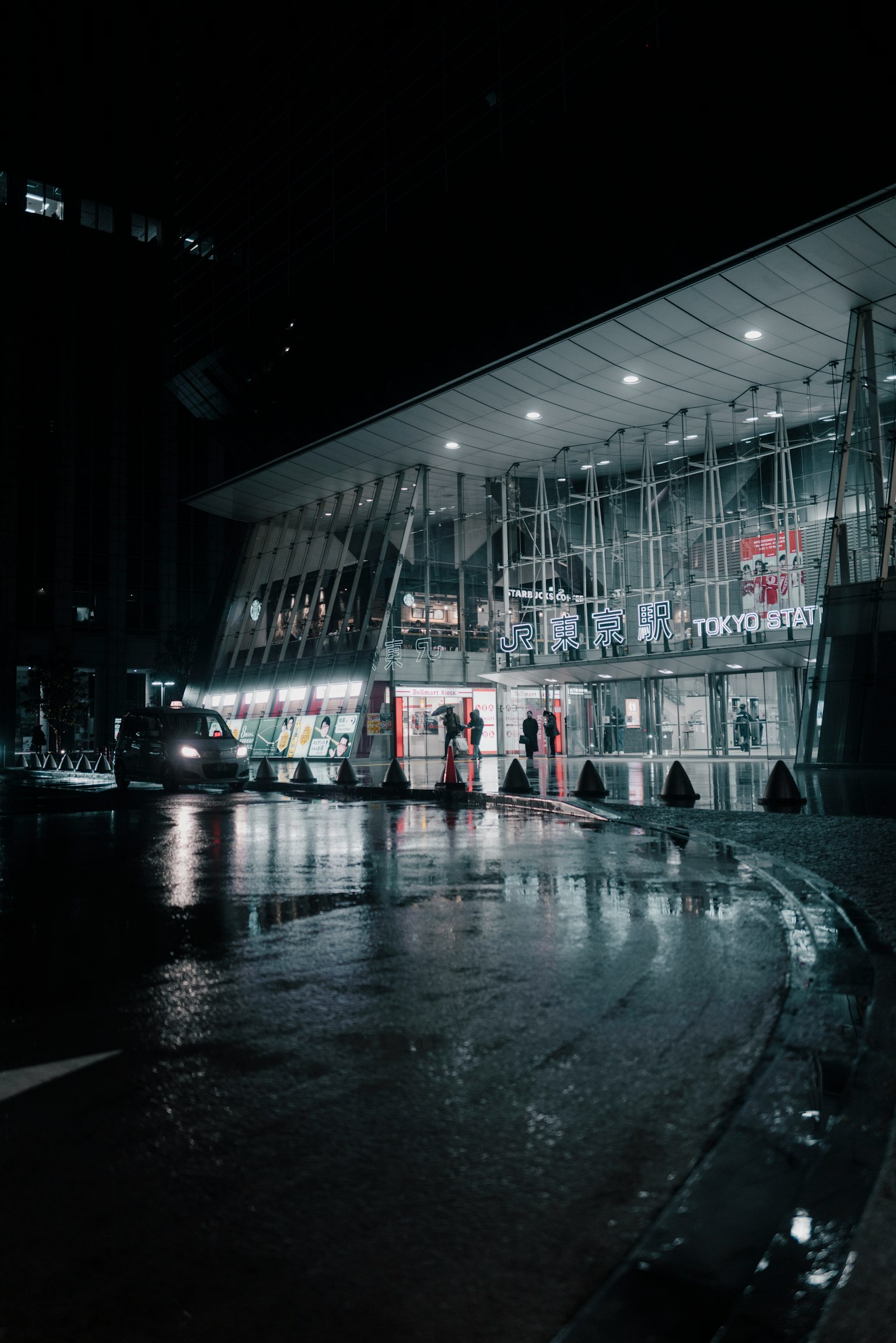 夜間城市環境中的現代建築外觀 濕滑的道路和人們的輪廓營造出氛圍