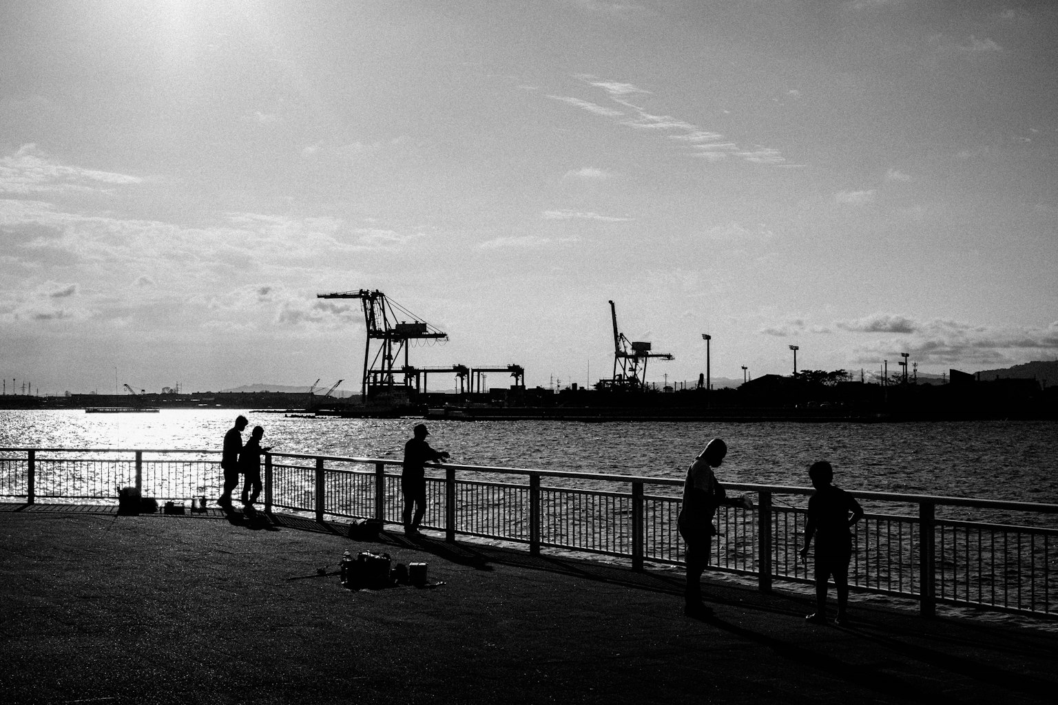 Silhouette of people standing at a waterfront in black and white