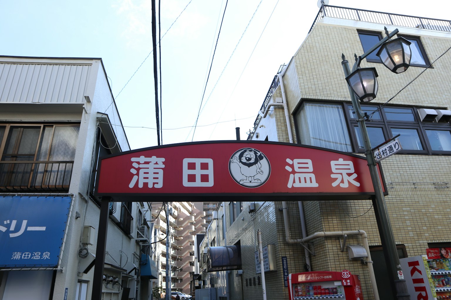 Insegna rossa per Kamata Onsen con edifici circostanti