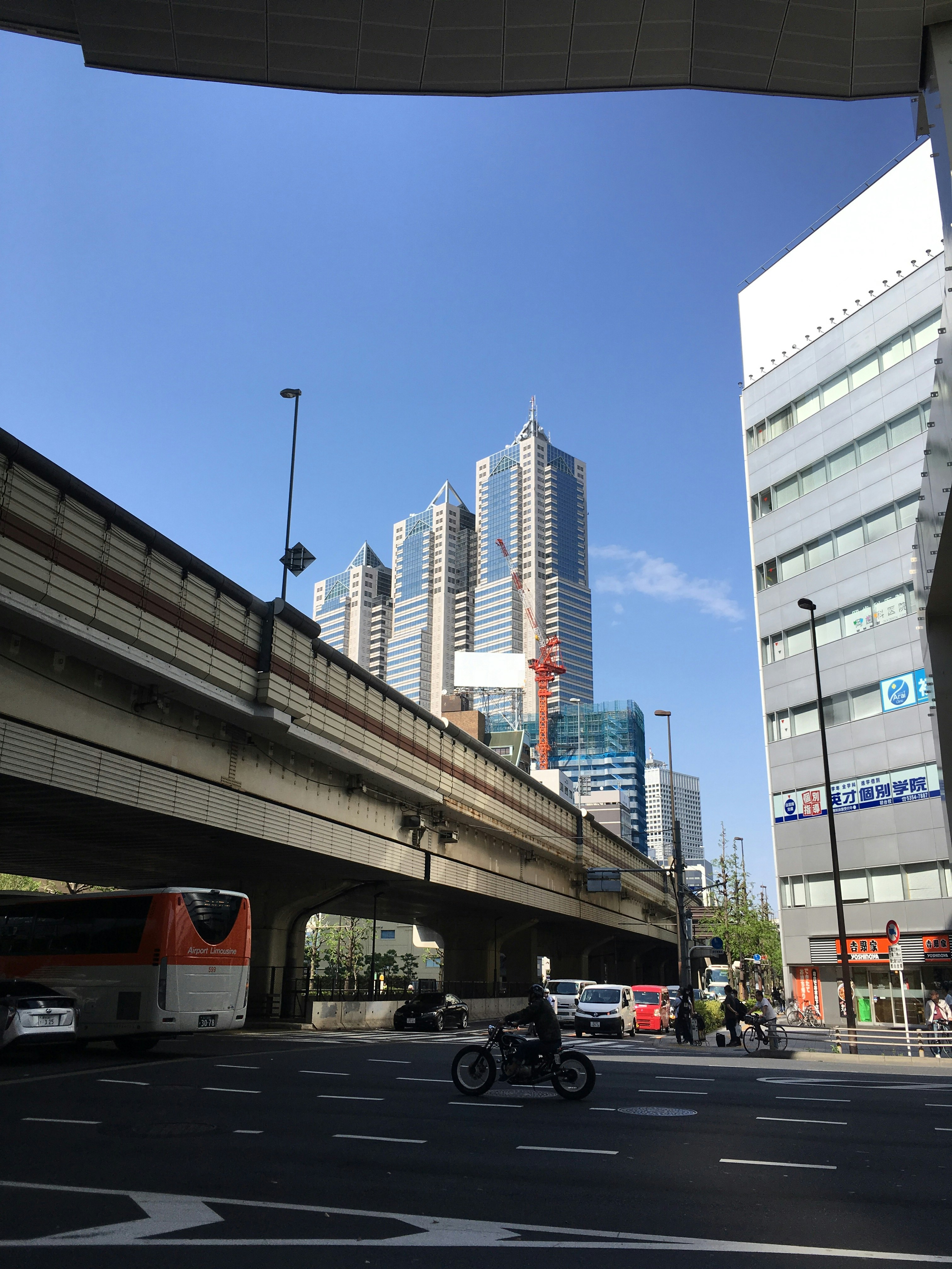 sepeda motor di bawah jalan layang dengan gedung perkantoran kota
