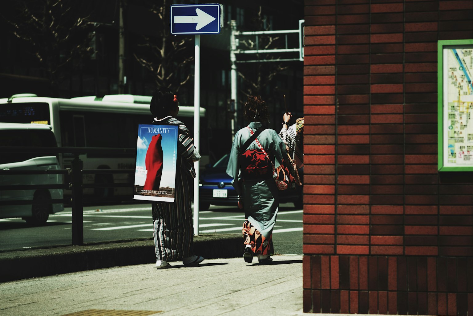 兩位穿著和服的女性在街上走過 可見指示牌和磚牆