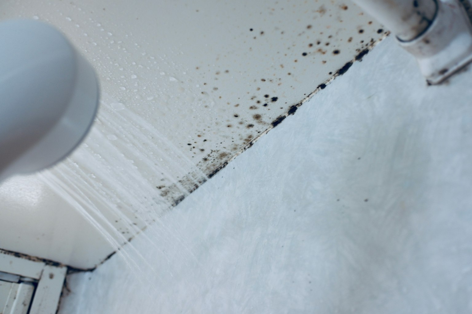 Eau s'écoulant sur une surface blanche avec de la moisissure sur le mur