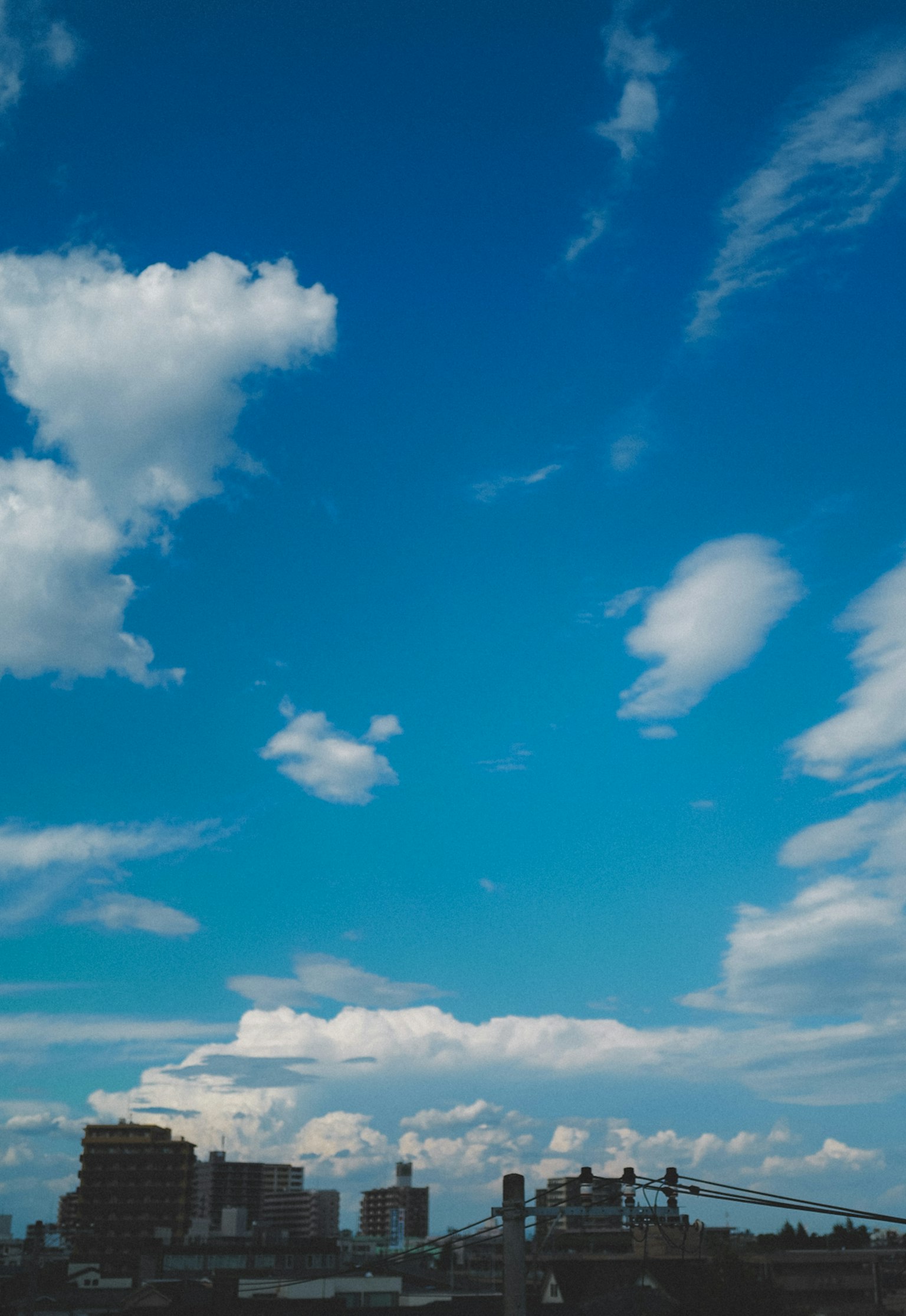 Ligne d'horizon de la ville sous un ciel bleu vif avec des nuages blancs duveteux