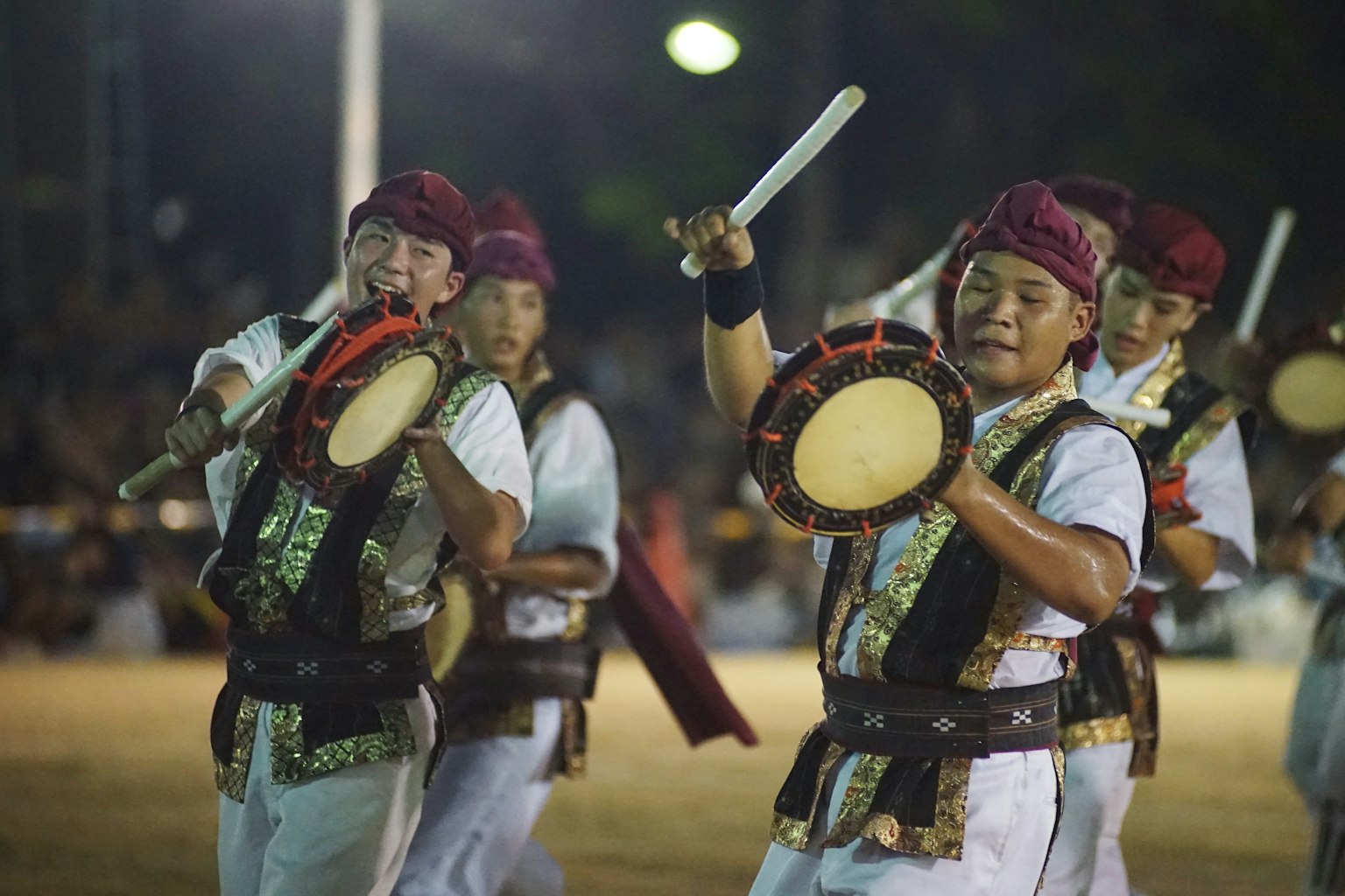 Uomini che suonano i tamburi durante una performance di danza tradizionale di notte