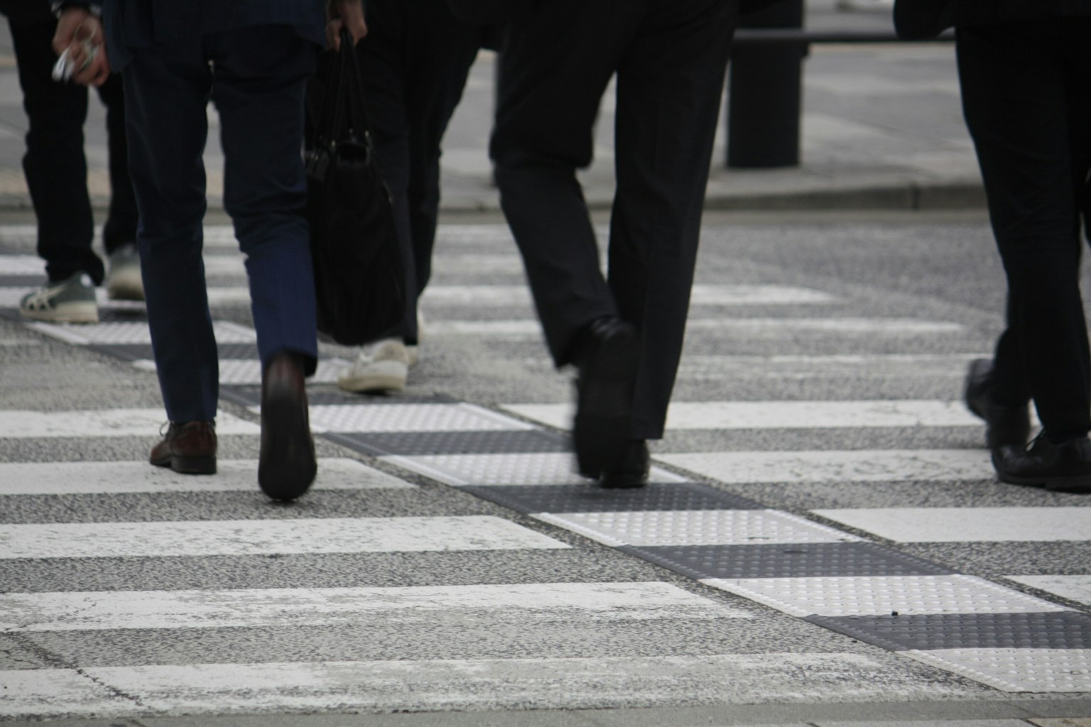 People crossing a pedestrian crosswalk showing the feet of men in suits