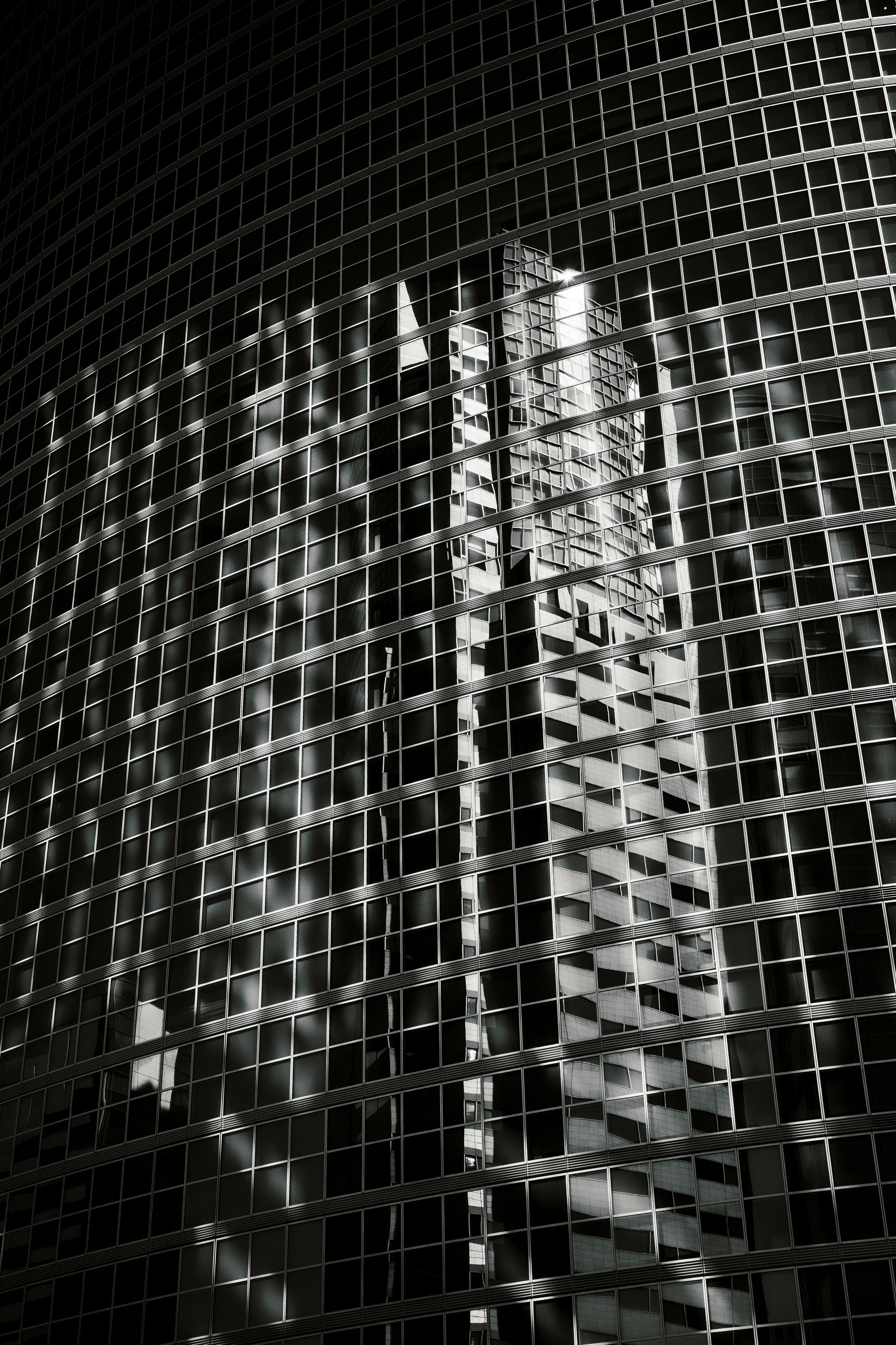 eine Hochhausfassade mit gitterartigen Fenstern und reflektierendem Licht