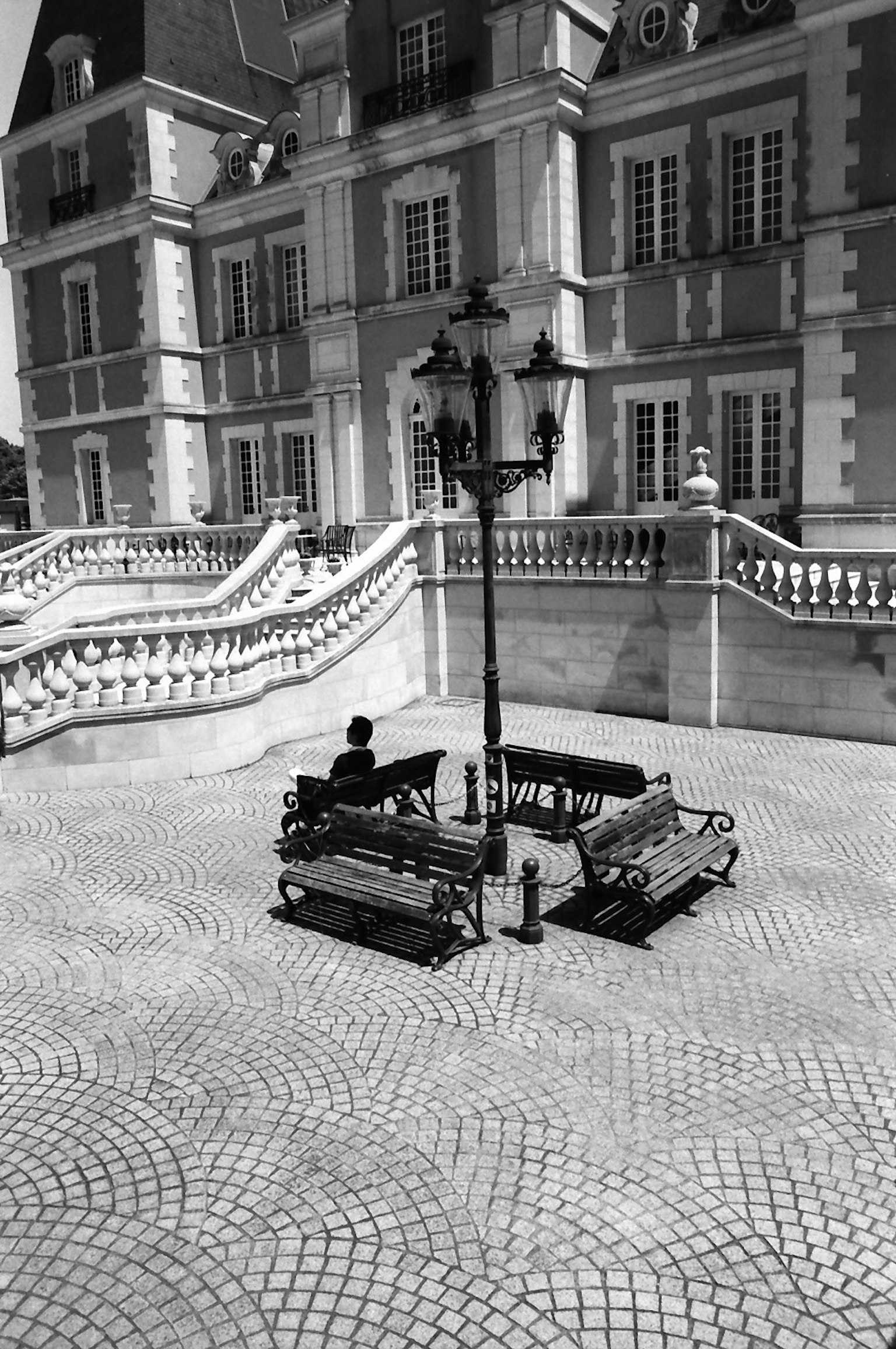 A square with benches and a street lamp in front of a beautiful building