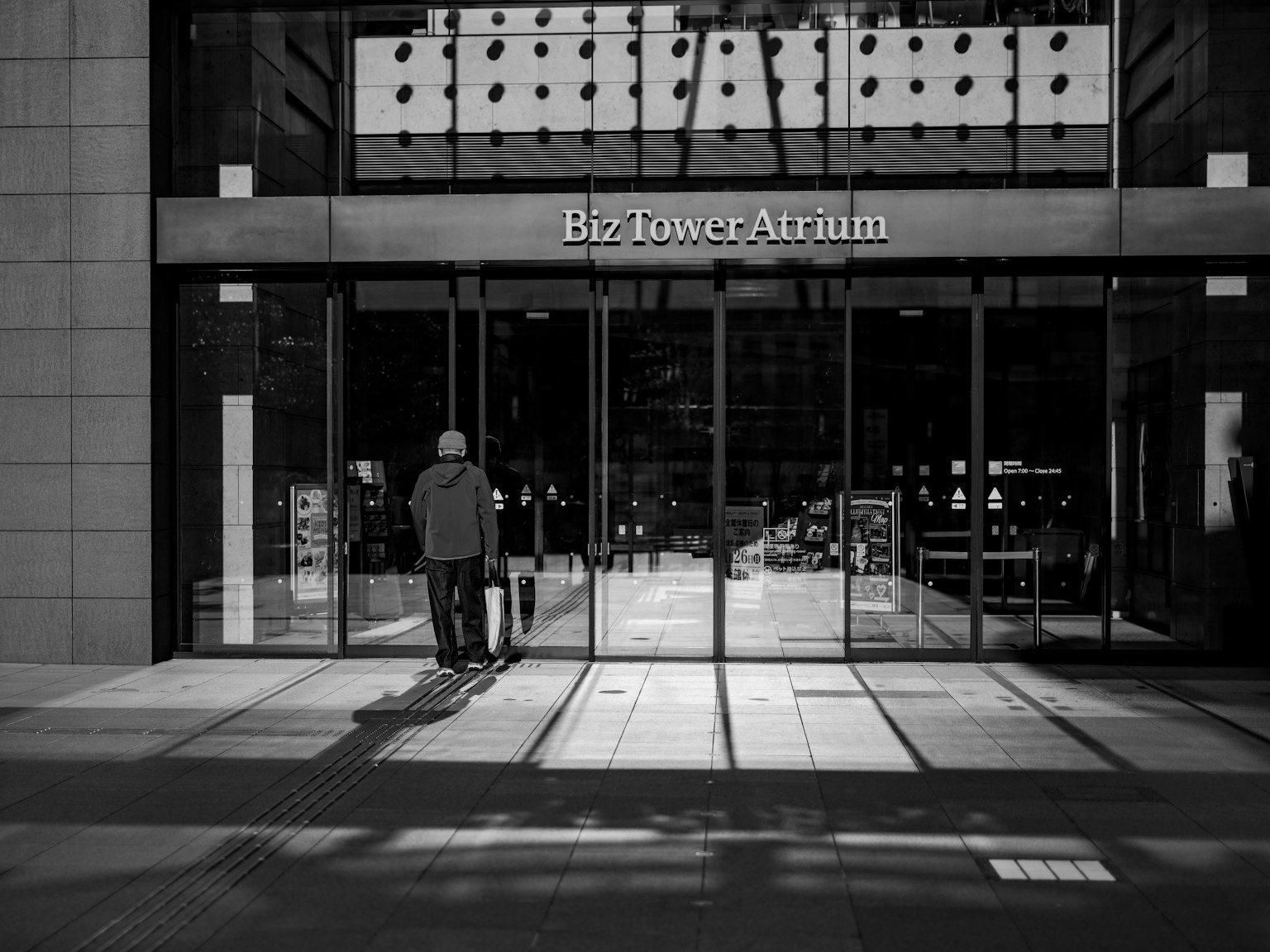 Foto in bianco e nero di persone che camminano all'ingresso di Biz Tower Atrium