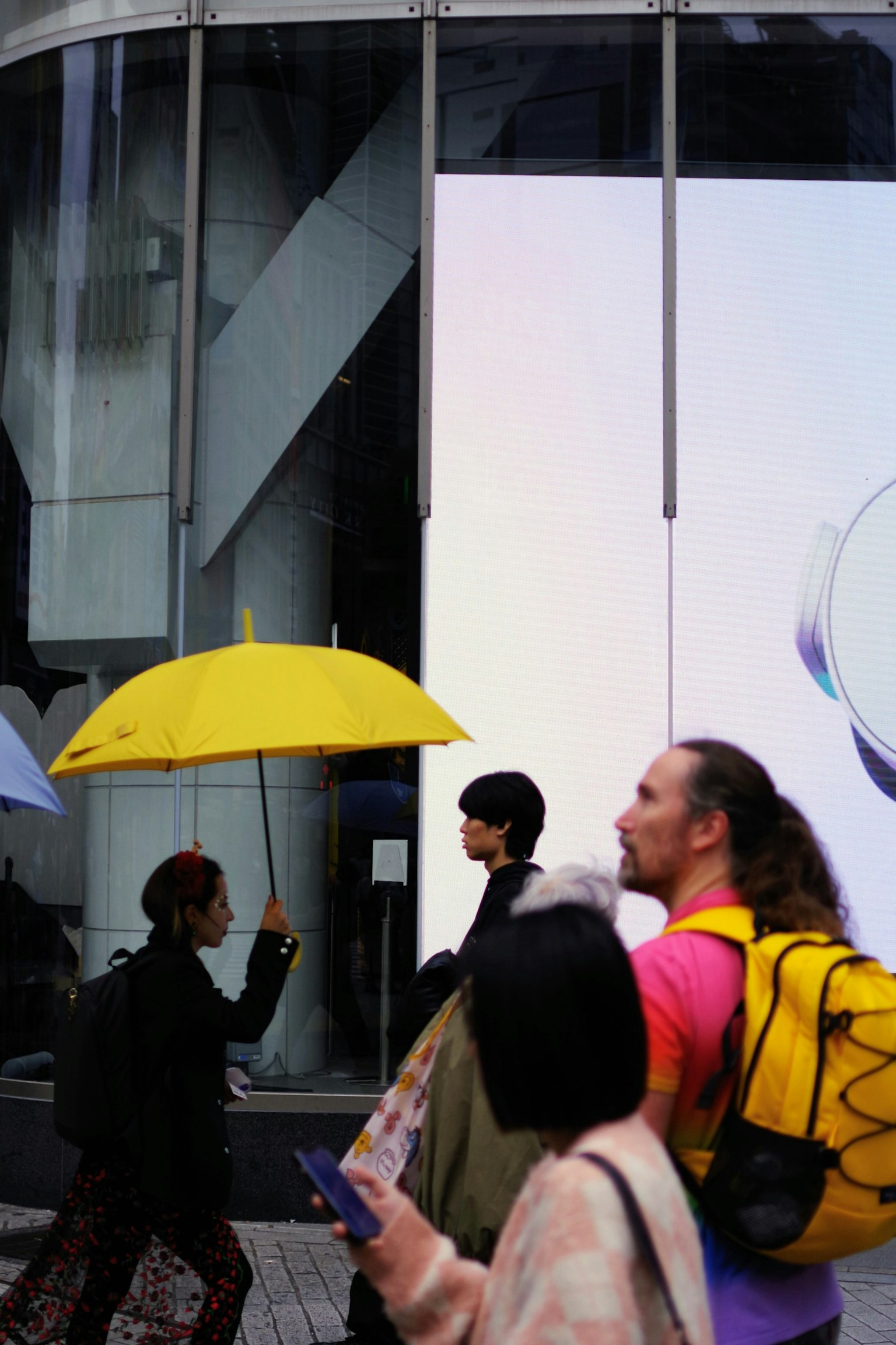 Des personnes marchant devant un bâtiment avec un parapluie jaune