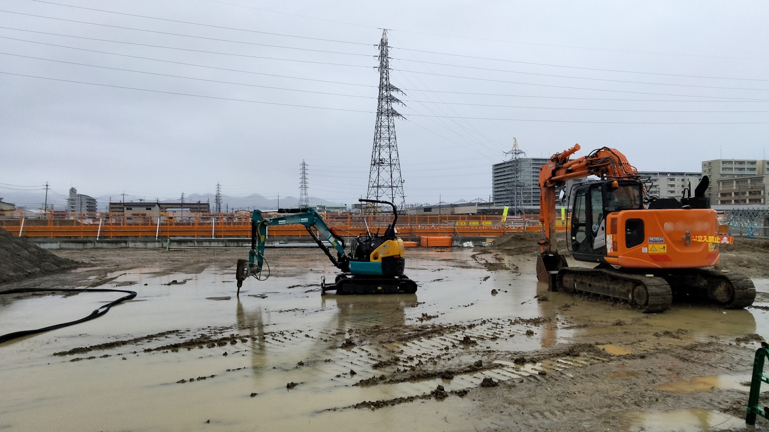 Sitio de construcción con maquinaria pesada y una torre eléctrica