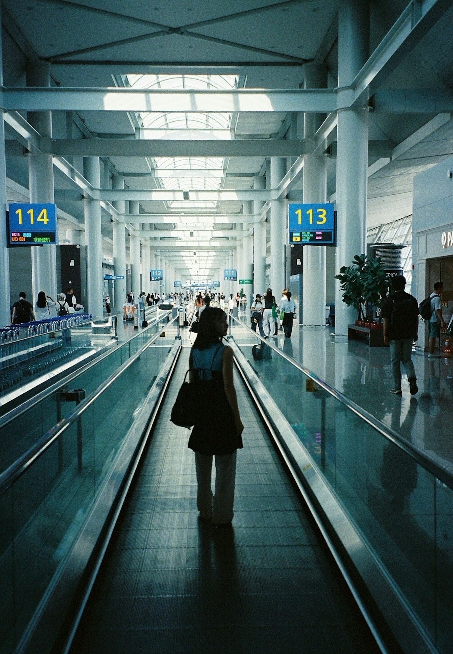 공항 내부에서 사람이 이동 보도를 걷고 있는 모습 밝은 조명과 현대적인 건축