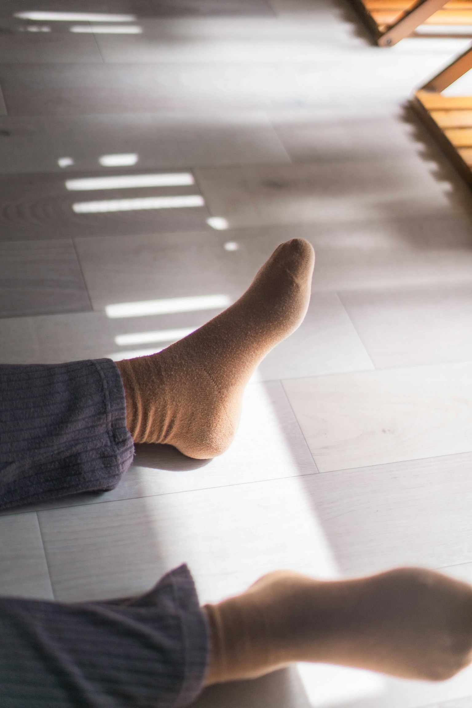 Pieds portant des chaussettes de couleur douce reposant sur un sol avec des rayures de lumière