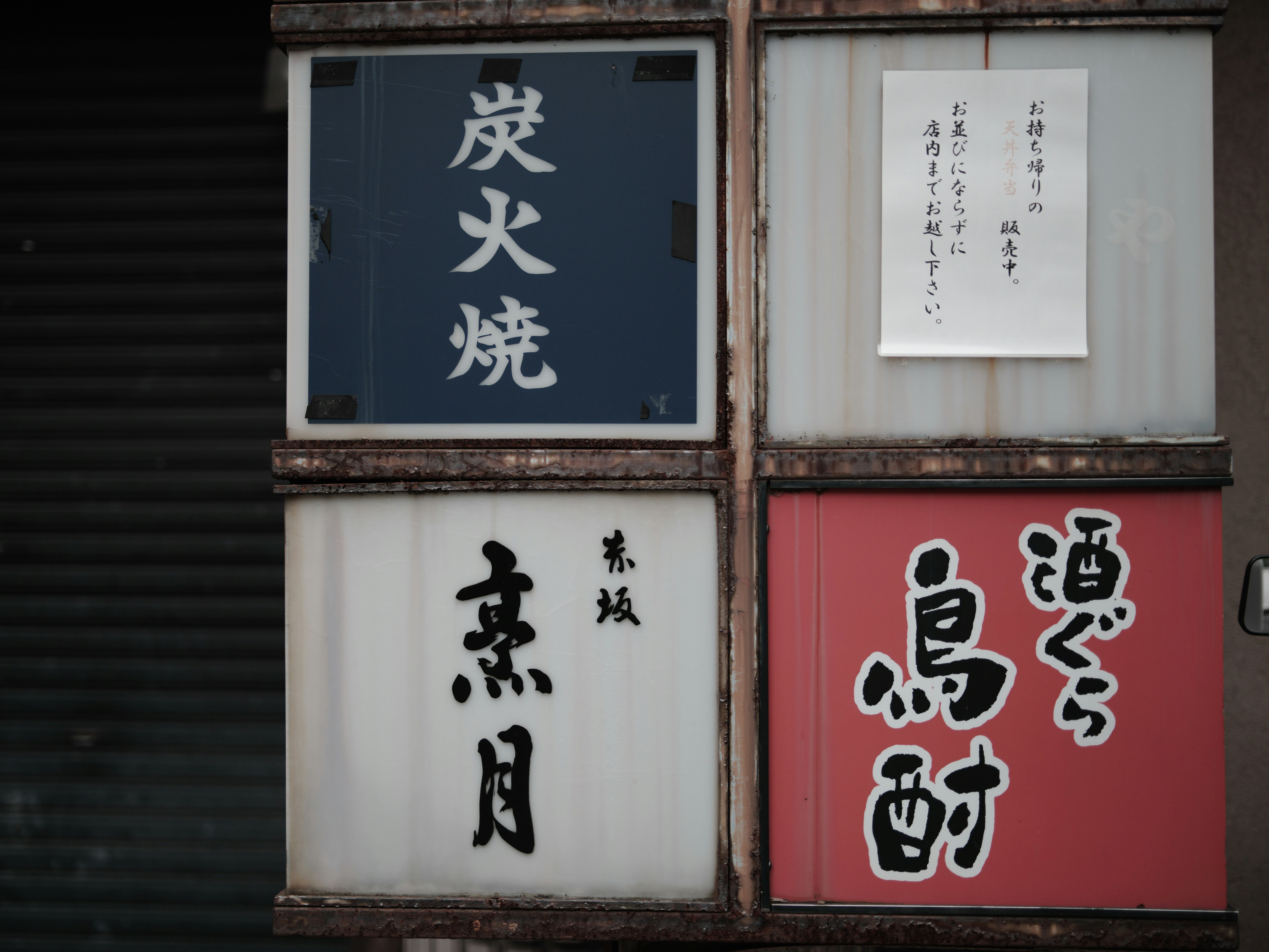 青と赤の看板が並ぶ商店街の軒先